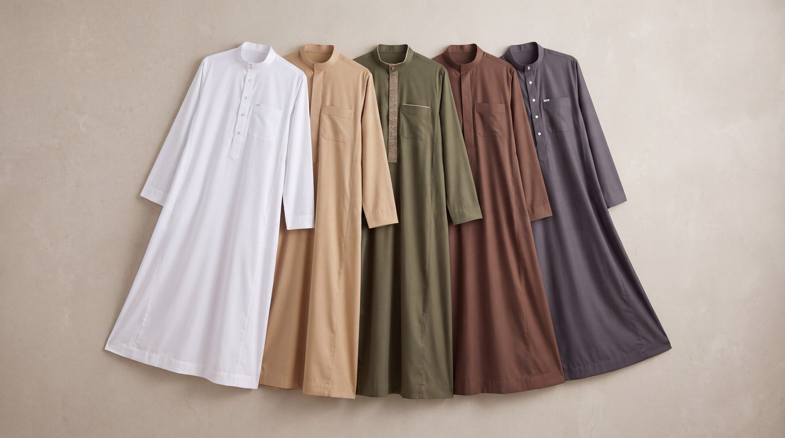 Five thobes in different colors hanging on a wall