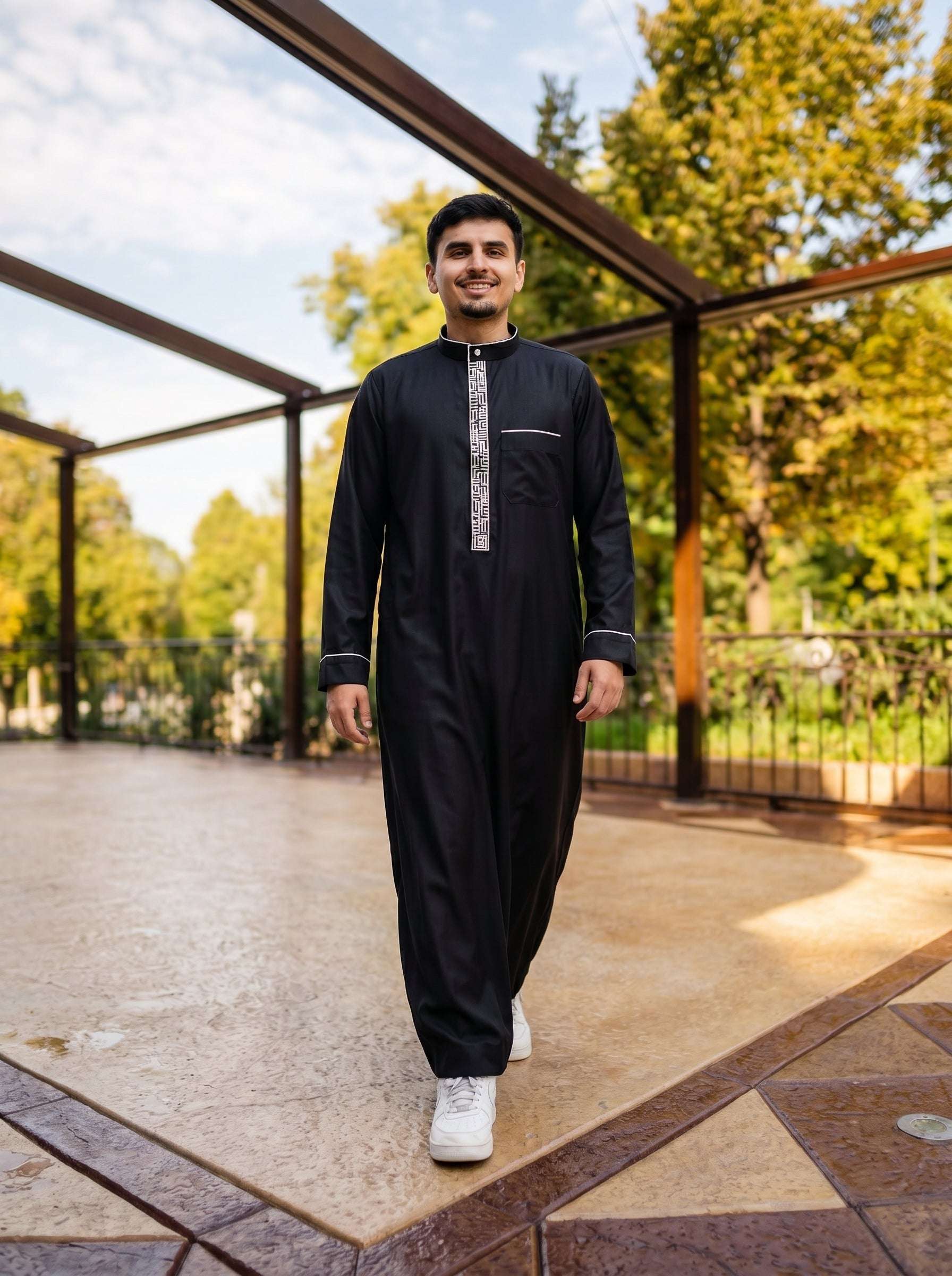 Full-length black embroidered thobe with contrast trim, walking shot
