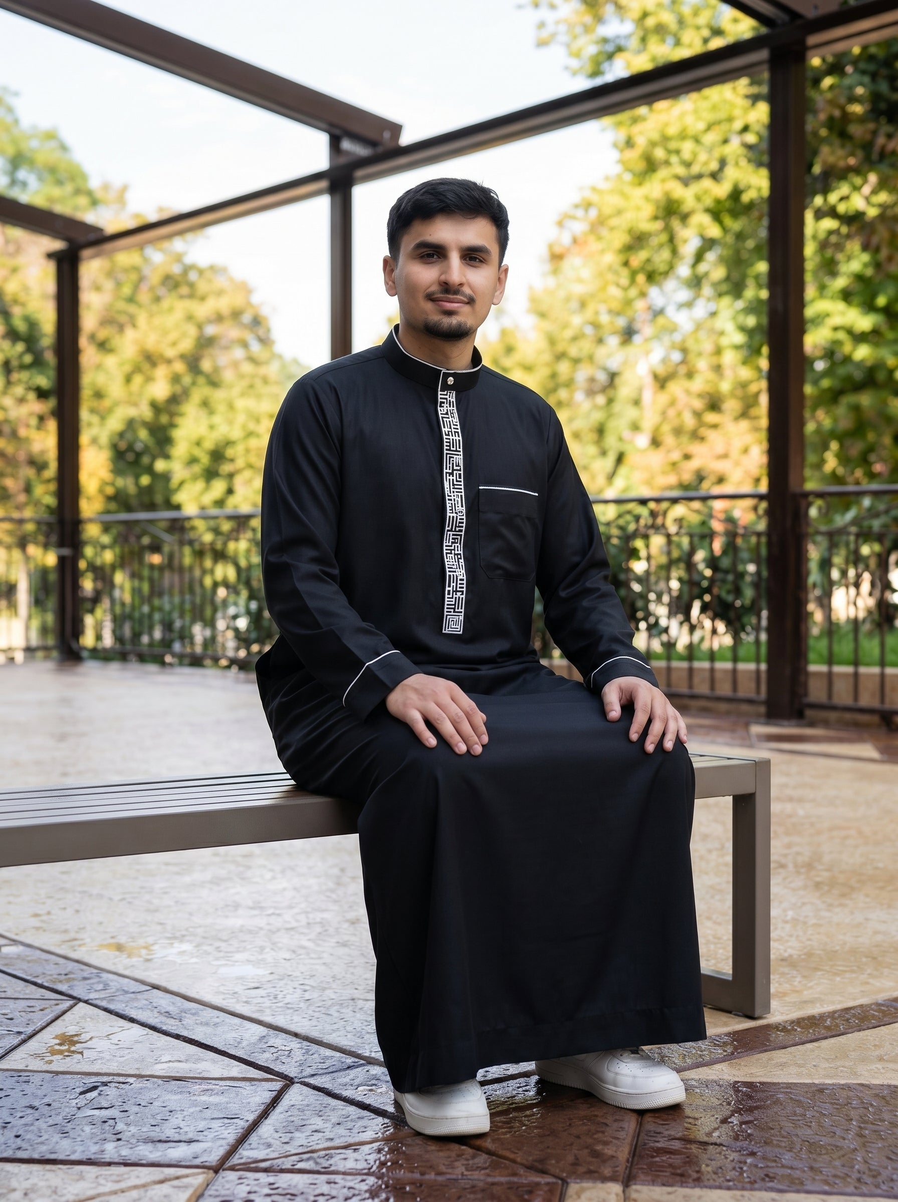 Editorial fashion shot of black hooded thobe adjusting cuff, lifestyle modest wear inspired by Shukr and Burda clothing quality, available at The Topiwala Chicago USA Shopify store.