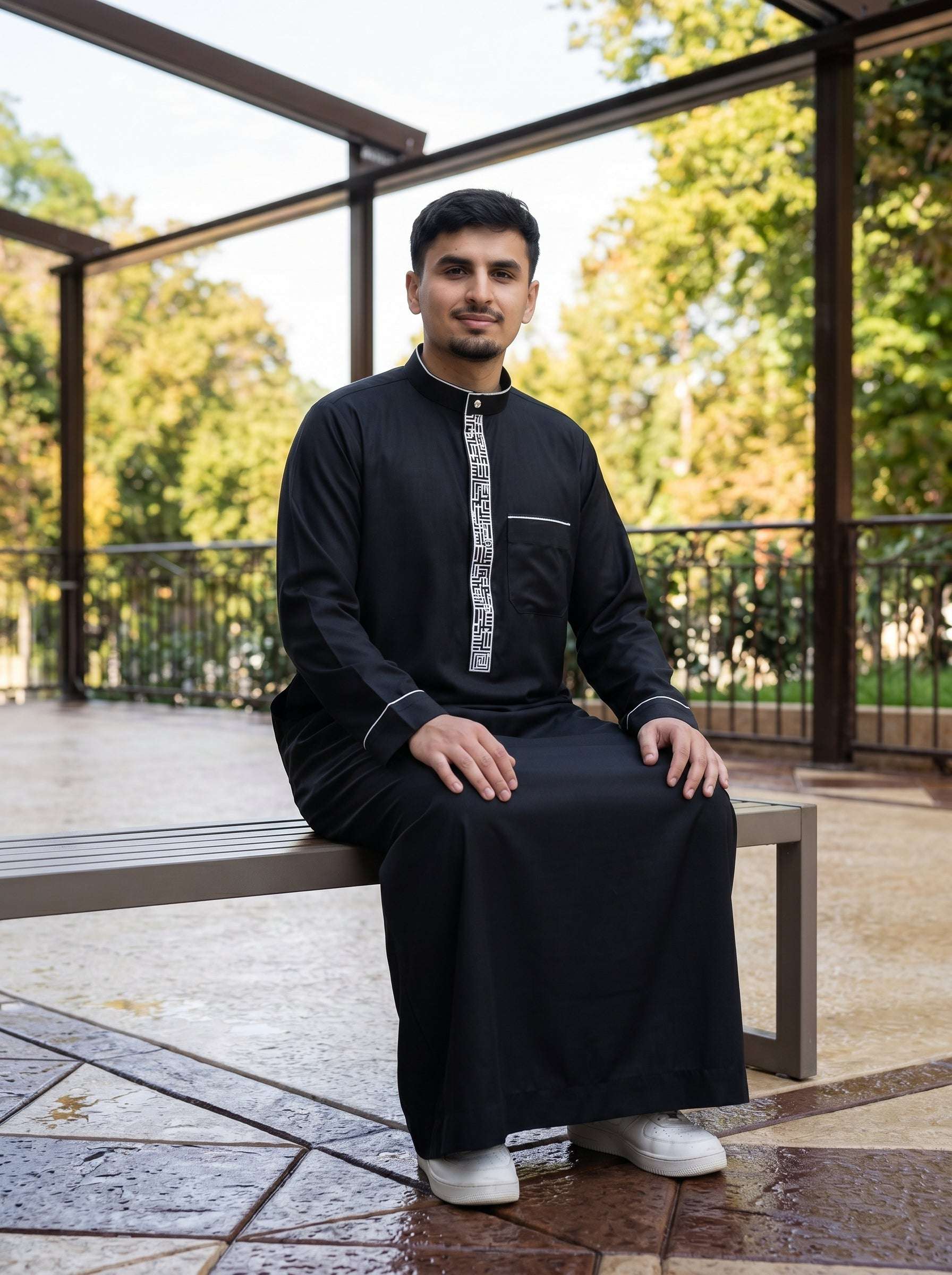 Man adjusting the cuff of the black embroidered thobe, modest menswear lifestyle shot