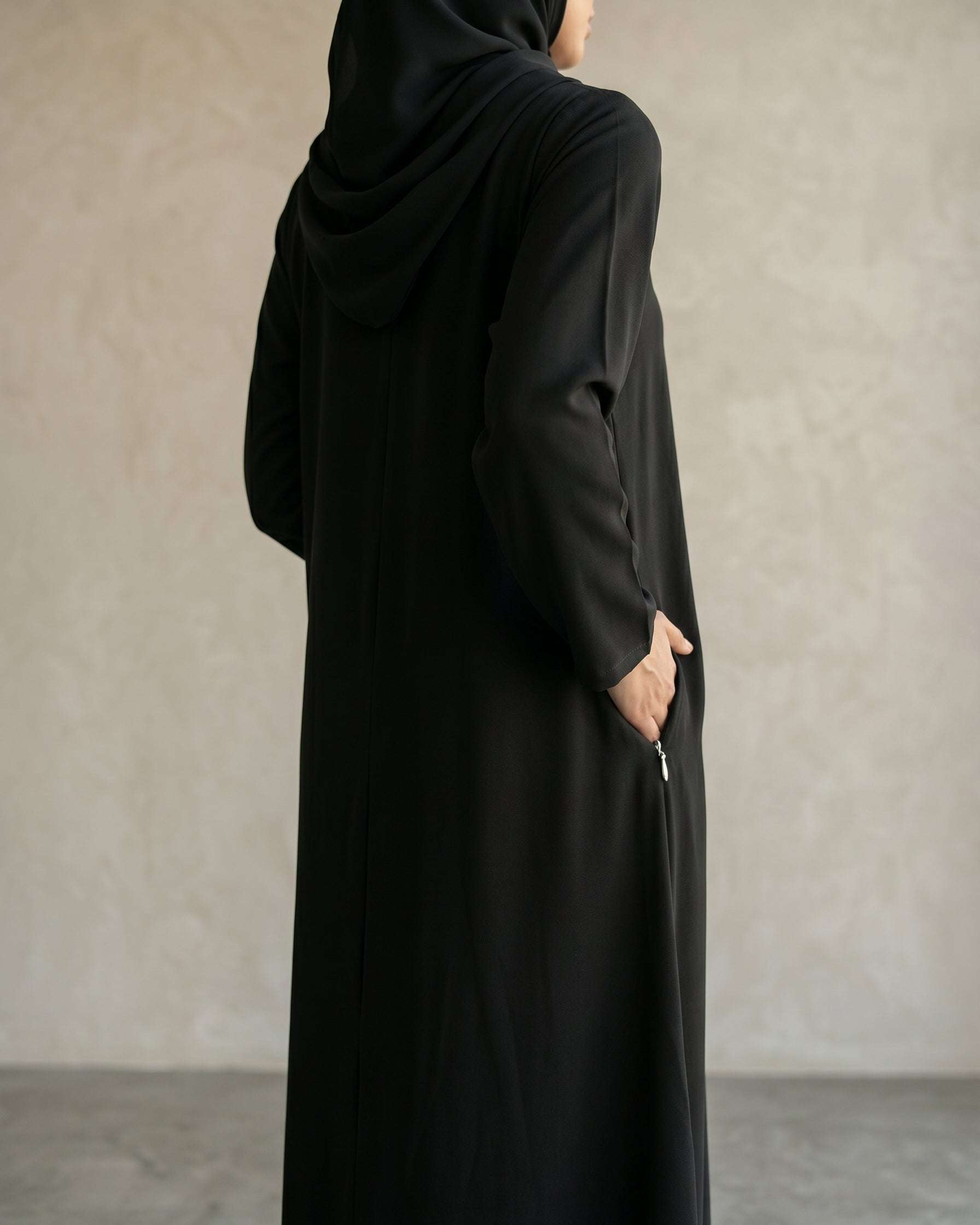 Macro close up of the clean slit neckline and internal size tag of the premium black abaya school uniform, practical modest wear for female students and staff.