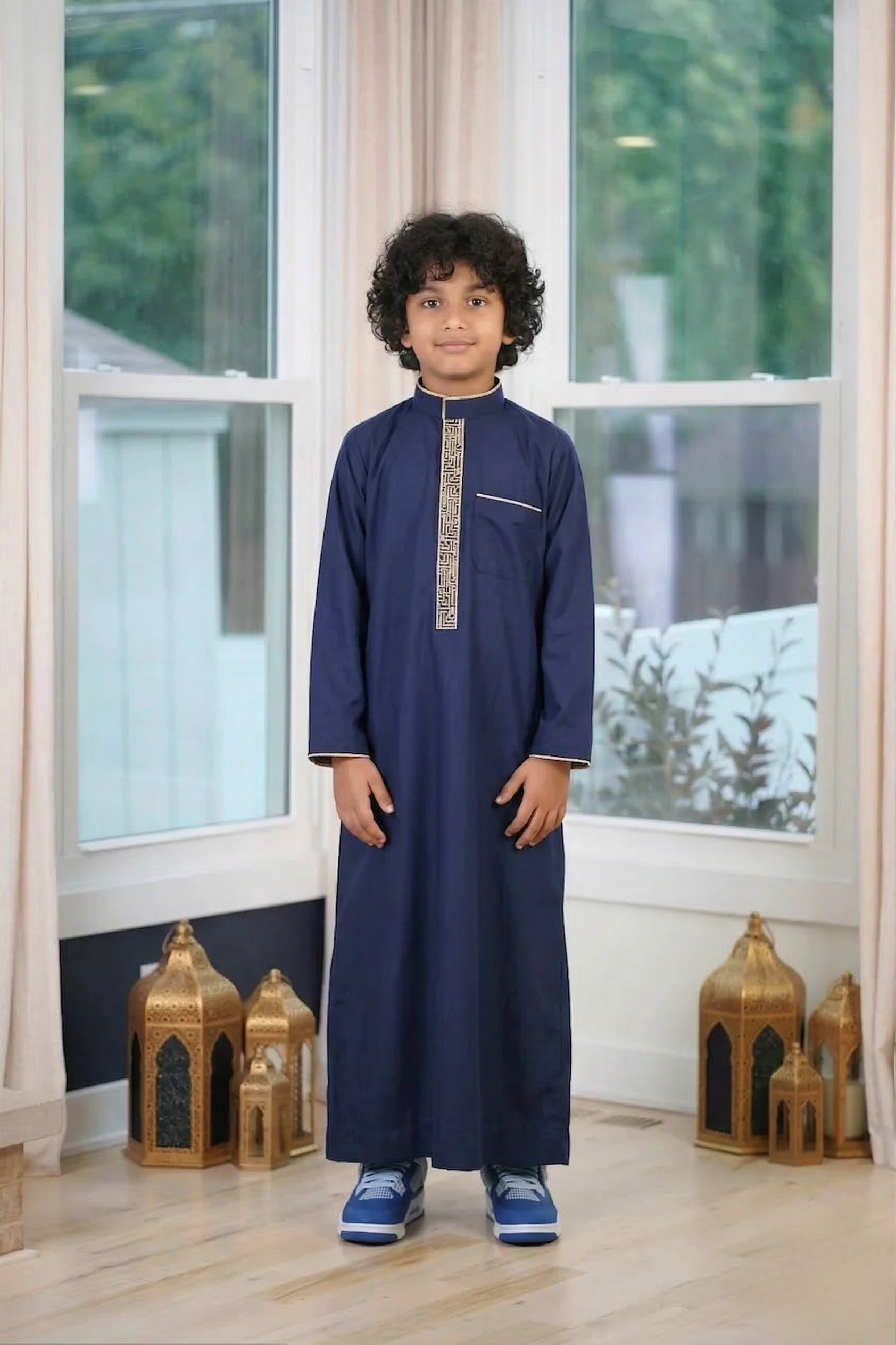 Muslim boy modeling a navy blue embroidered boys thobe with gold chest details. A stylish kids jubbah perfect for Eid outfits and Islamic clothing in the USA.