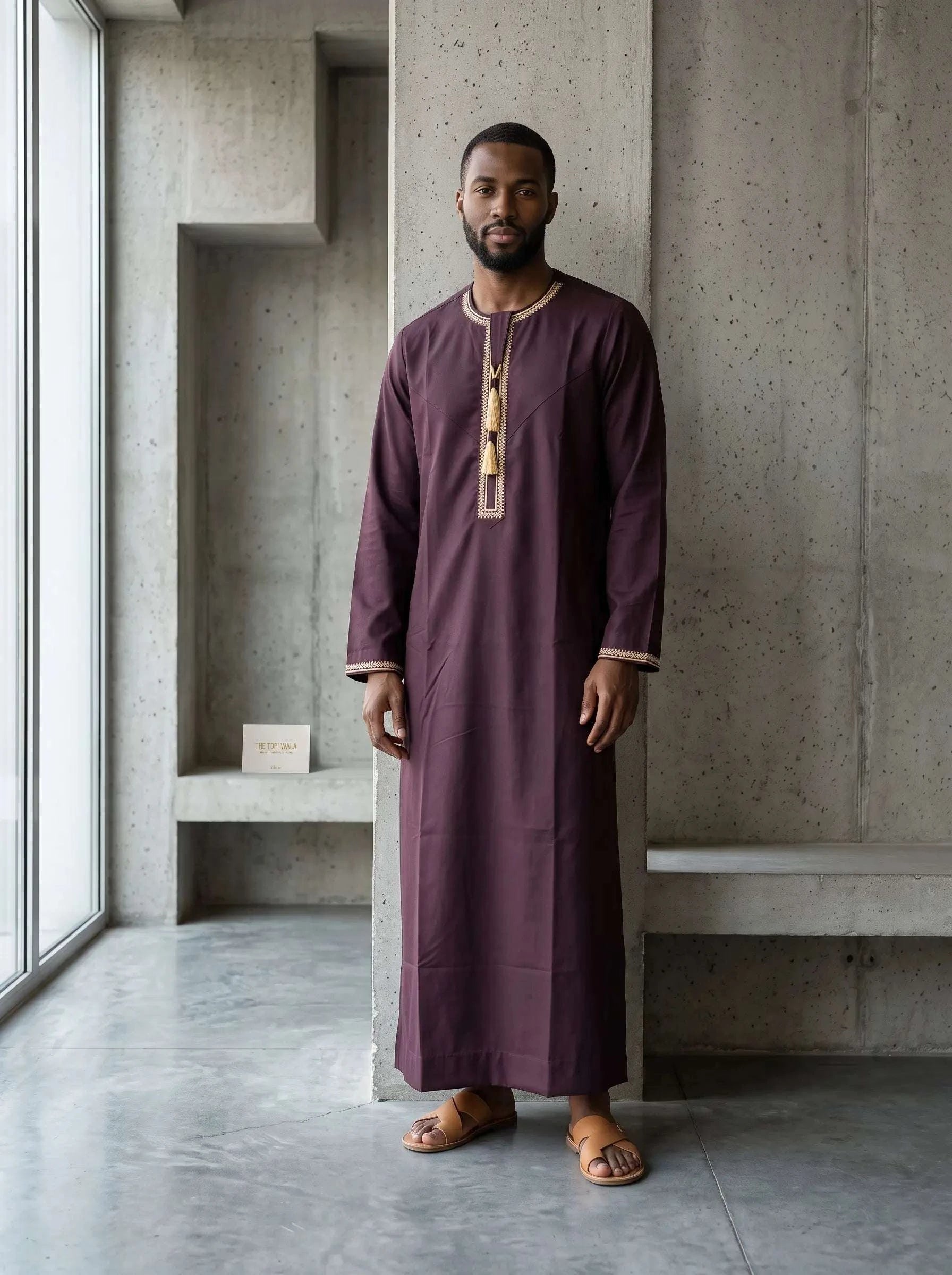 Burgundy Emirati thobe with a V-neck and tarboush for men, close-up of the fabric