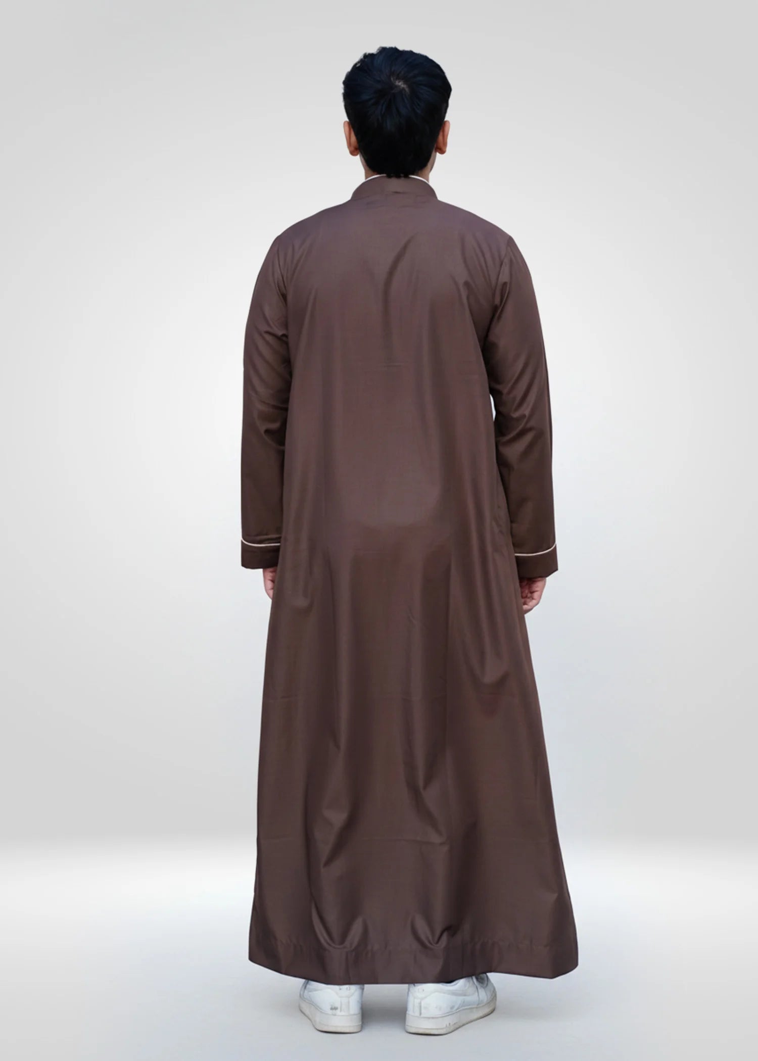 Lifestyle shot of a man wearing the chocolate brown embroidered thobe, looking elegant for a special event