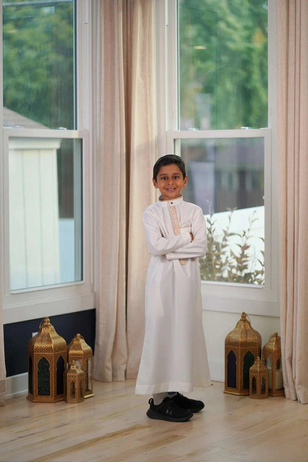 Cream and gold embroidered thobe for boys, worn by a model outdoors