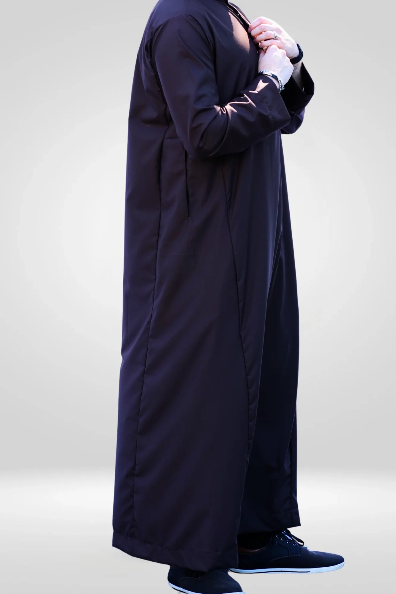Lifestyle shot of a man wearing the plain dark brown thobe, looking grounded and comfortable