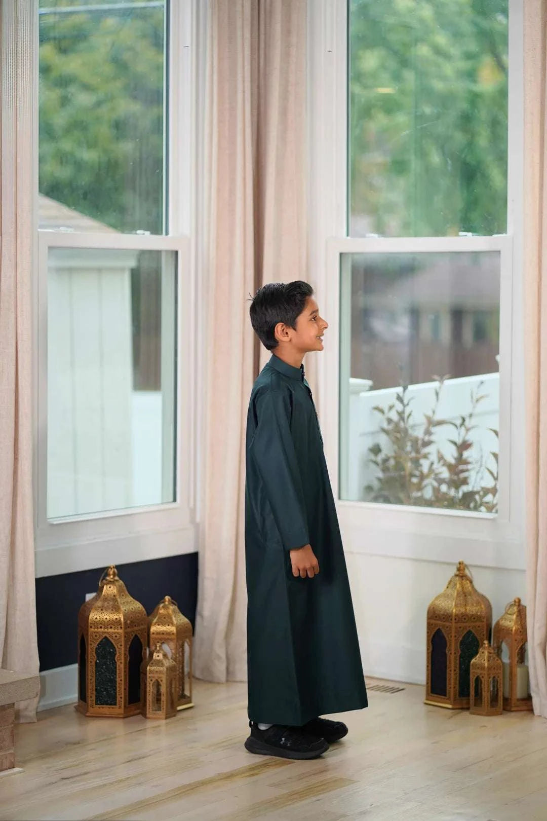 Dark green thobe for boys, worn by a model outdoors