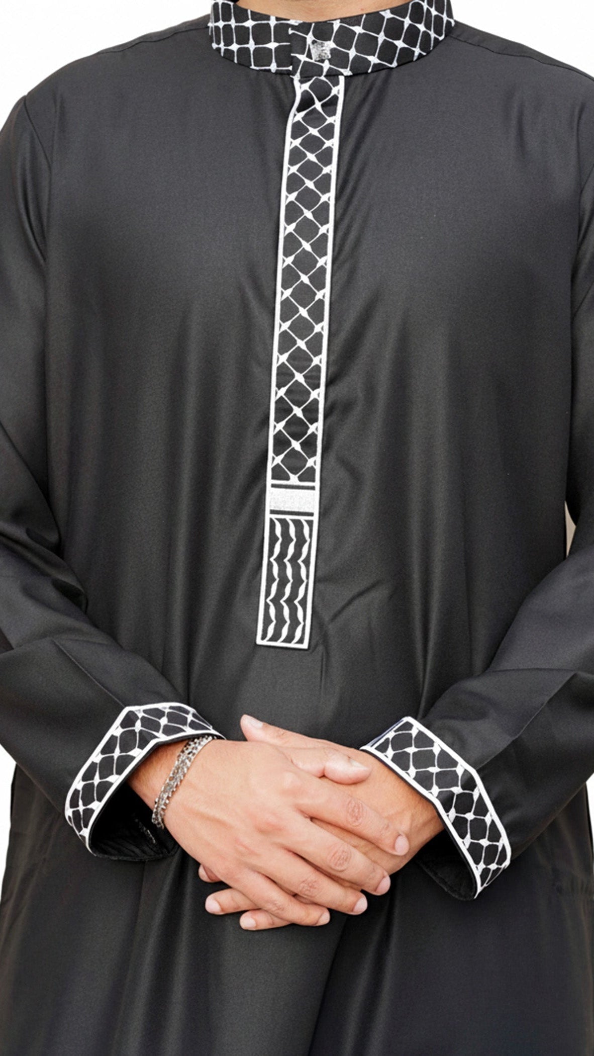 Lifestyle shot of a man wearing the black and white embroidered thobe, looking proud and stylish