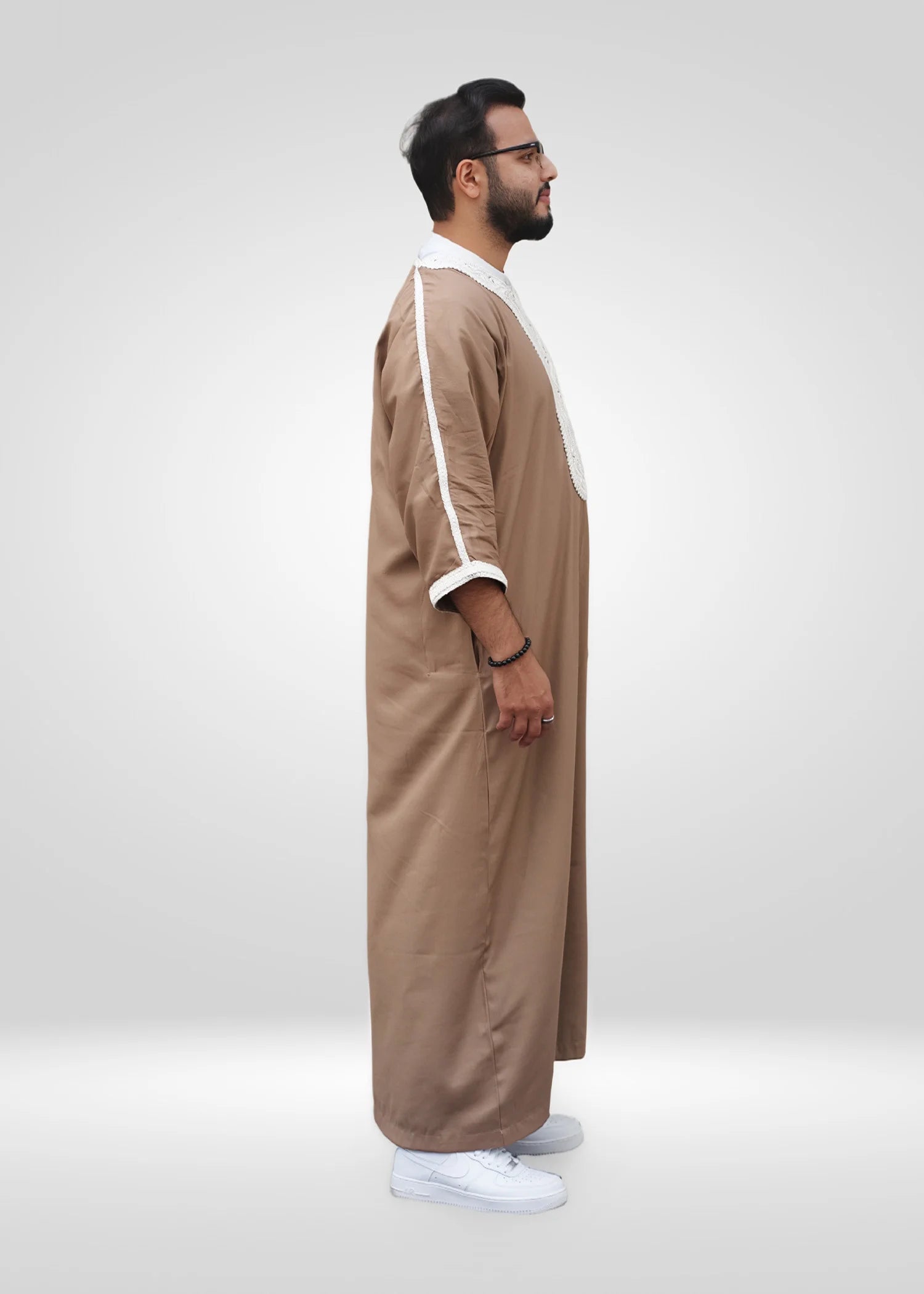 Macro shot of the premium fabric texture and white embroidery stitching on the men's thobe