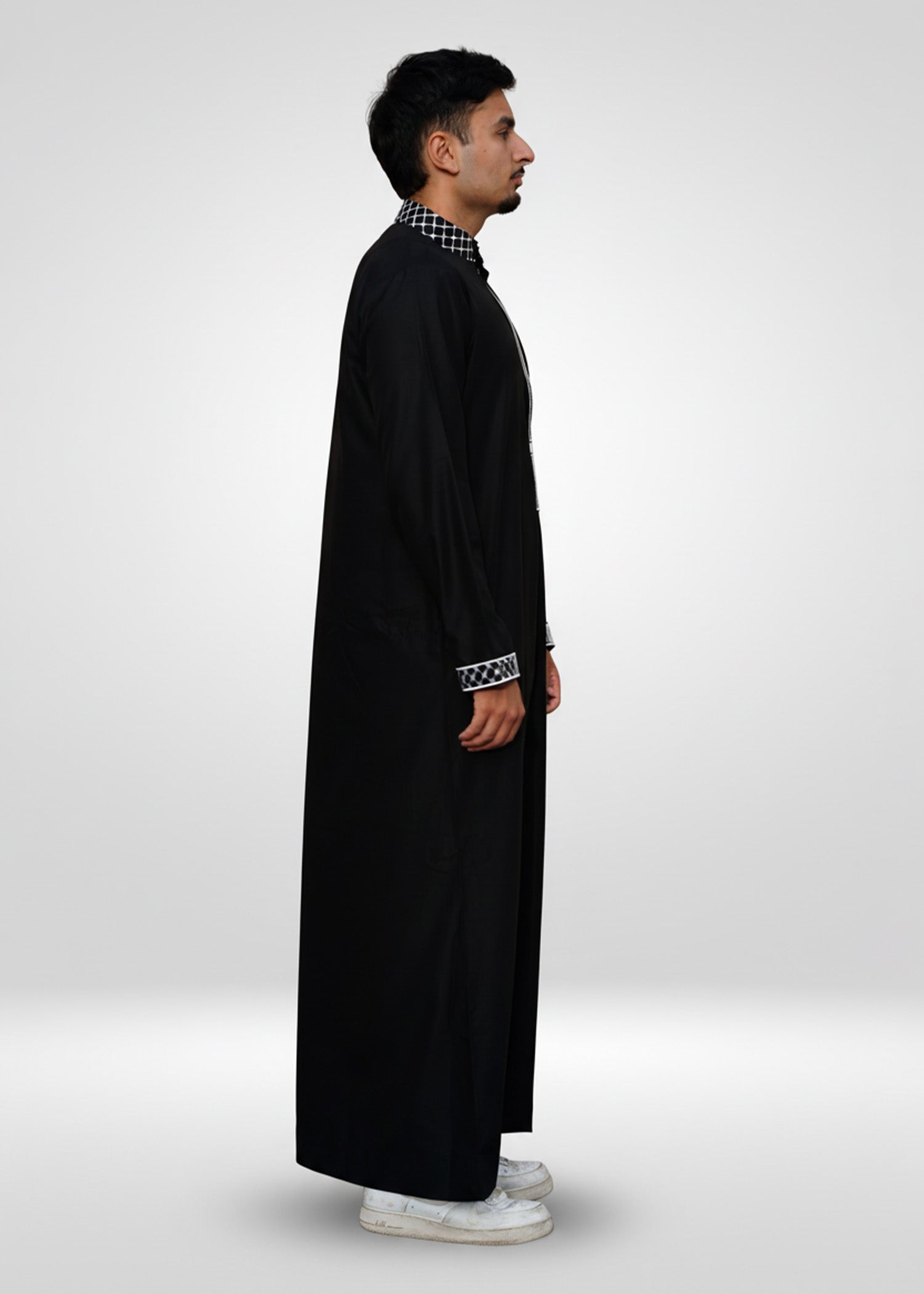 Detail shot of the sleeve cuff featuring matching black and white checkered embroidery on the black fabric