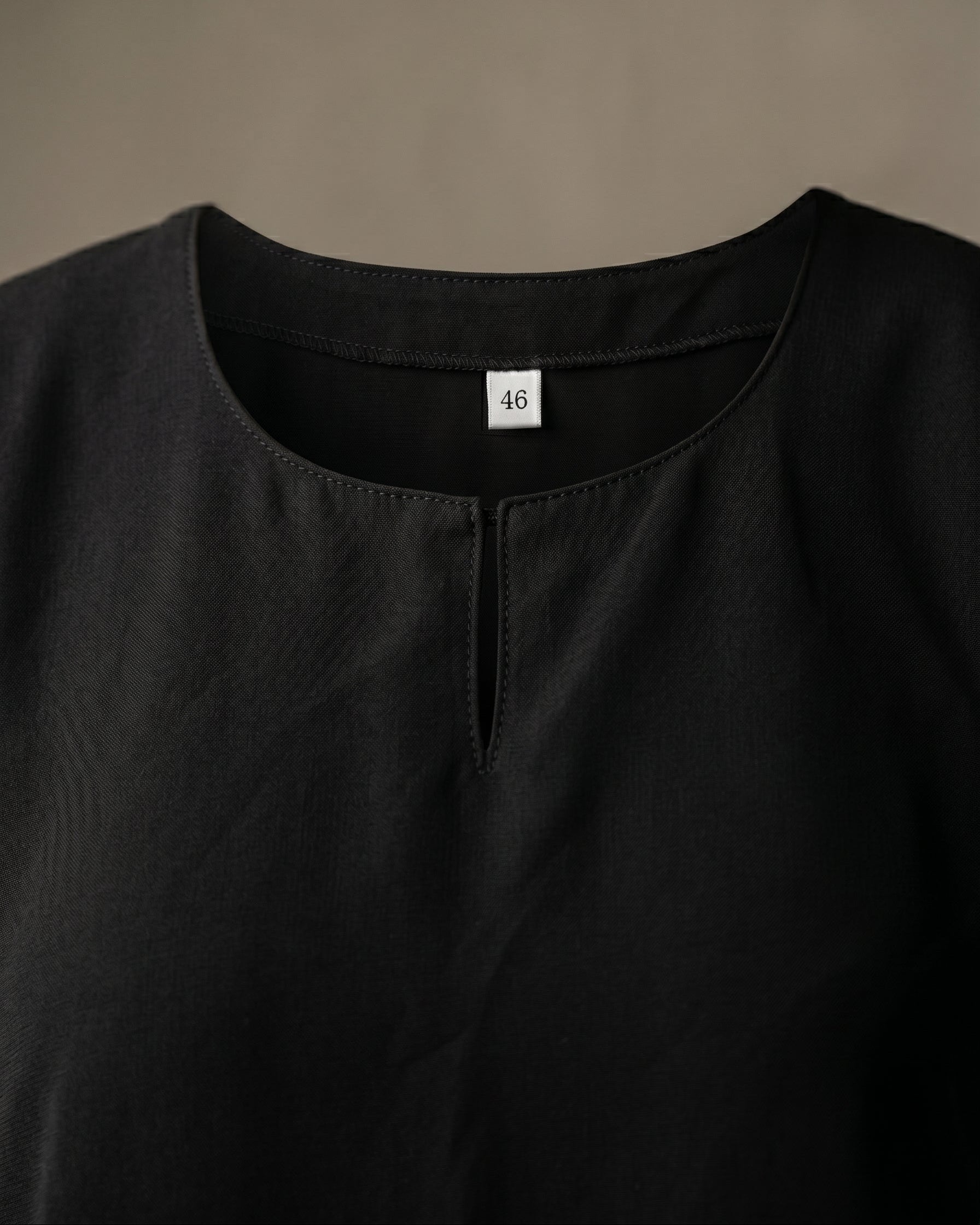 Full length back view of a woman wearing the official black abaya uniform and matching hijab looking out a window, modest Islamic school attire for girls and teachers.