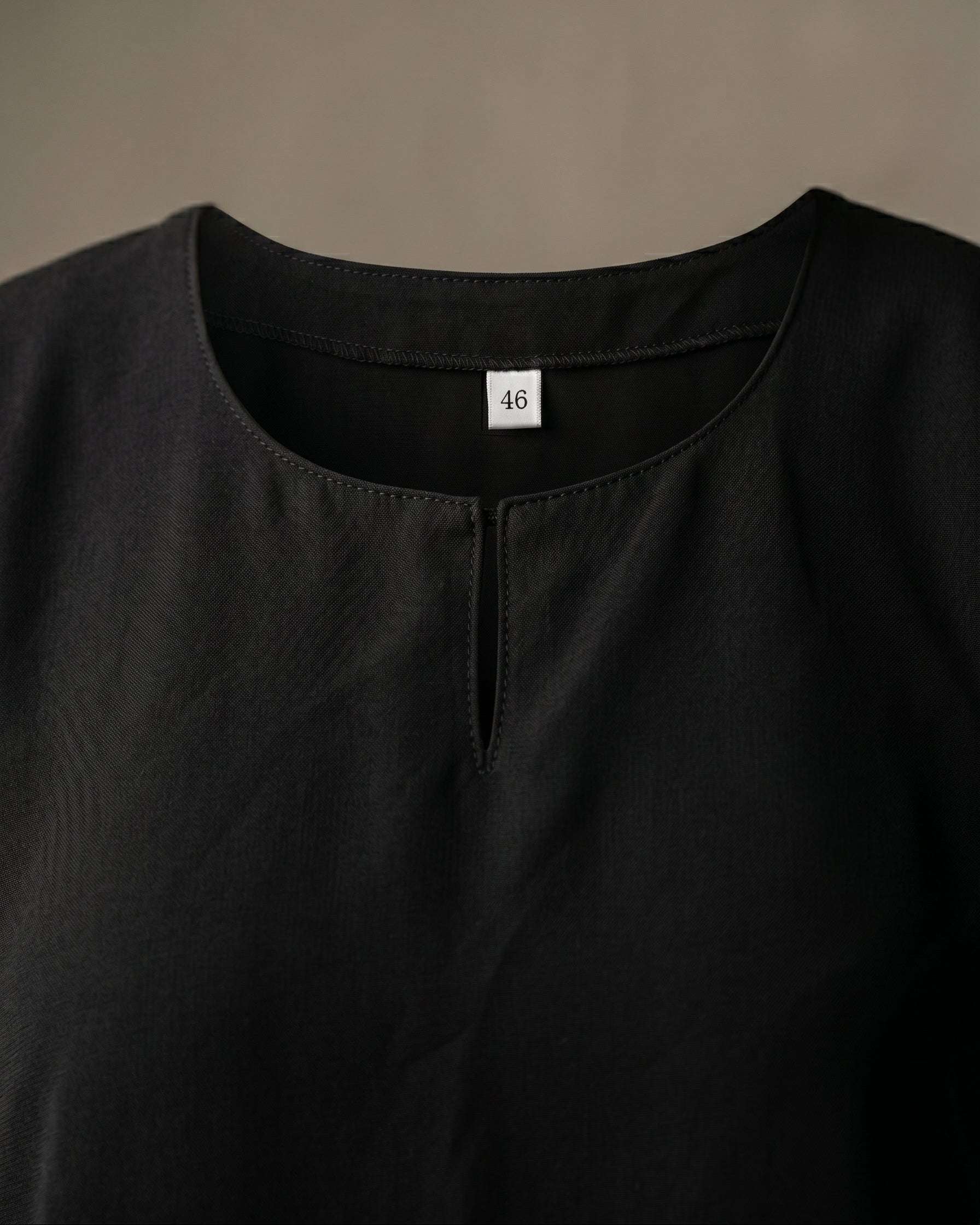 Full length back view of a woman wearing the official black abaya uniform and matching hijab looking out a window, modest Islamic school attire for girls and teachers.