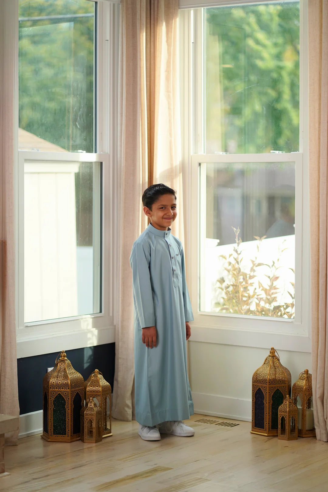 Close up of the mandarin collar and button placket on the ice blue boys thobe