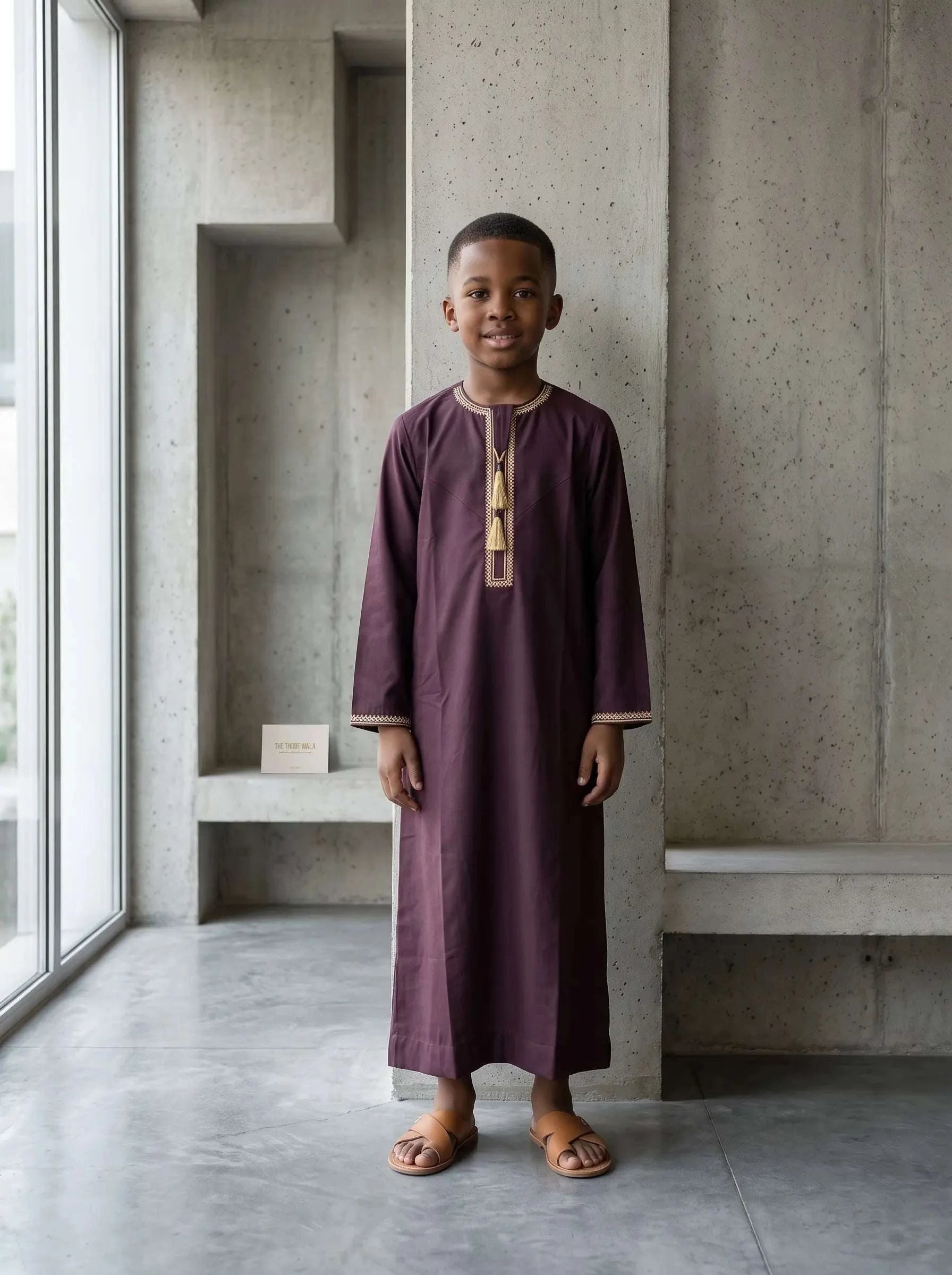Premium burgundy Emirati thobe for kids with tarboush tassel – rich maroon boys jubba featuring authentic UAE collarless V-neck design and refined embroidery. Best kids Emirati thobe USA for Eid, Jumu'ah, Nikkah and weddings. Affordable premium Islamic clothing for boys and Muslim kids fashion in sizes 18–50 from The Topiwala – making Sunnah clothing affordable. Shop boys maroon Dubai style thobe, kids kandura, kids omani thobe and modest wear for children online in the USA.