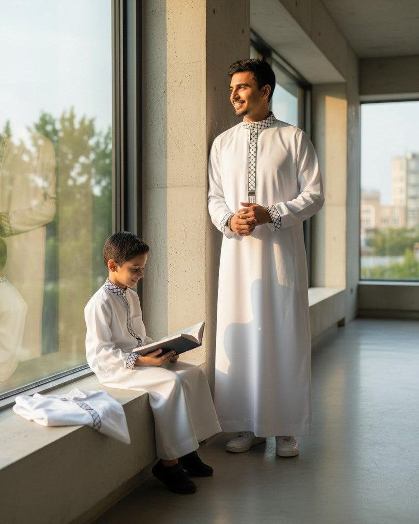 Matching white embroidered thobes for father and son. Premium Islamic clothing for men and boys. Modern Muslim family lifestyle, modest menswear, comfortable kids jubba, and elegant adult thobe with geometric collar details. Perfect Eid outfit and everyday Sunnah wear.