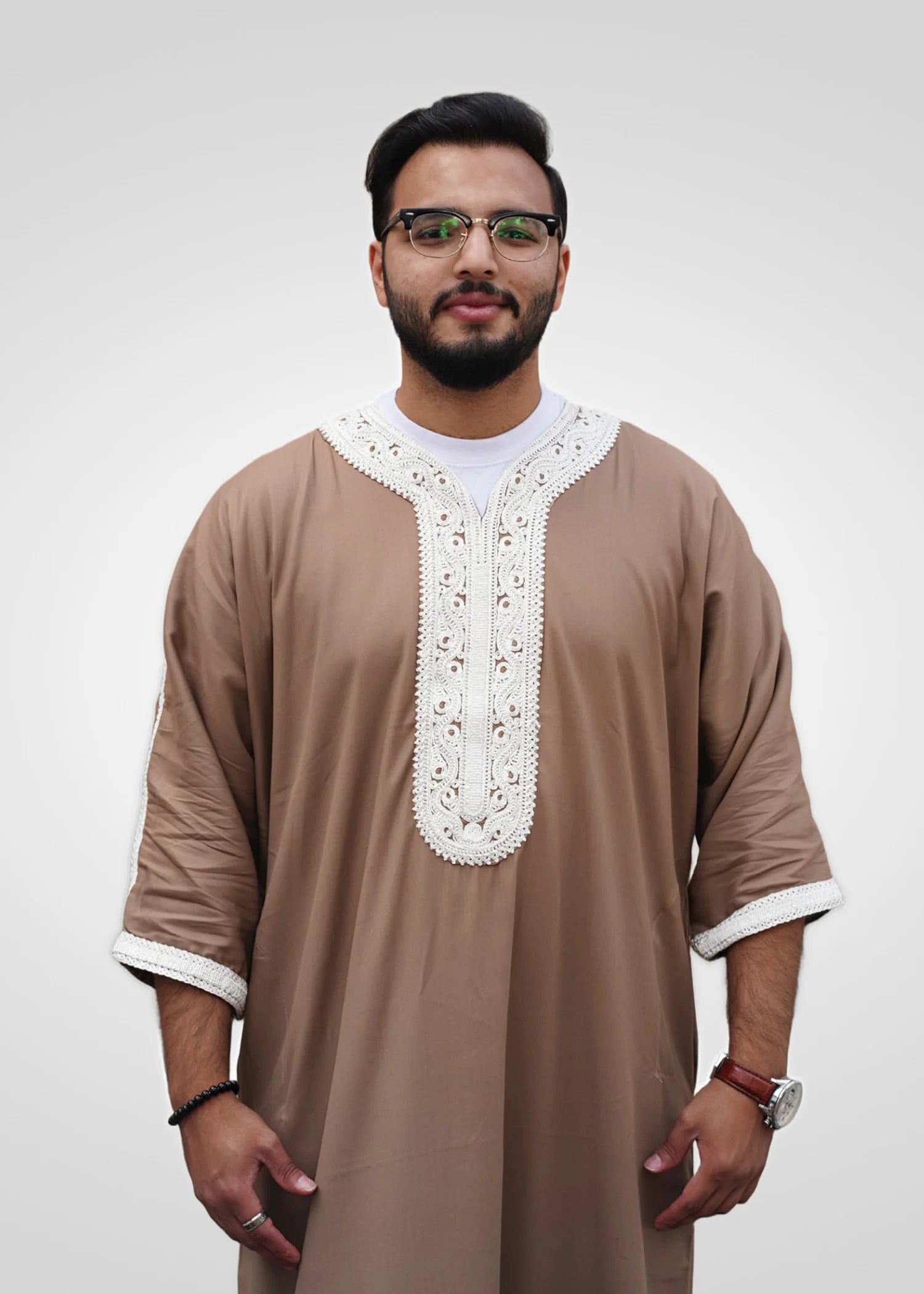 Close up of the intricate white embroidery on the chest and neckline of the beige men's thobe