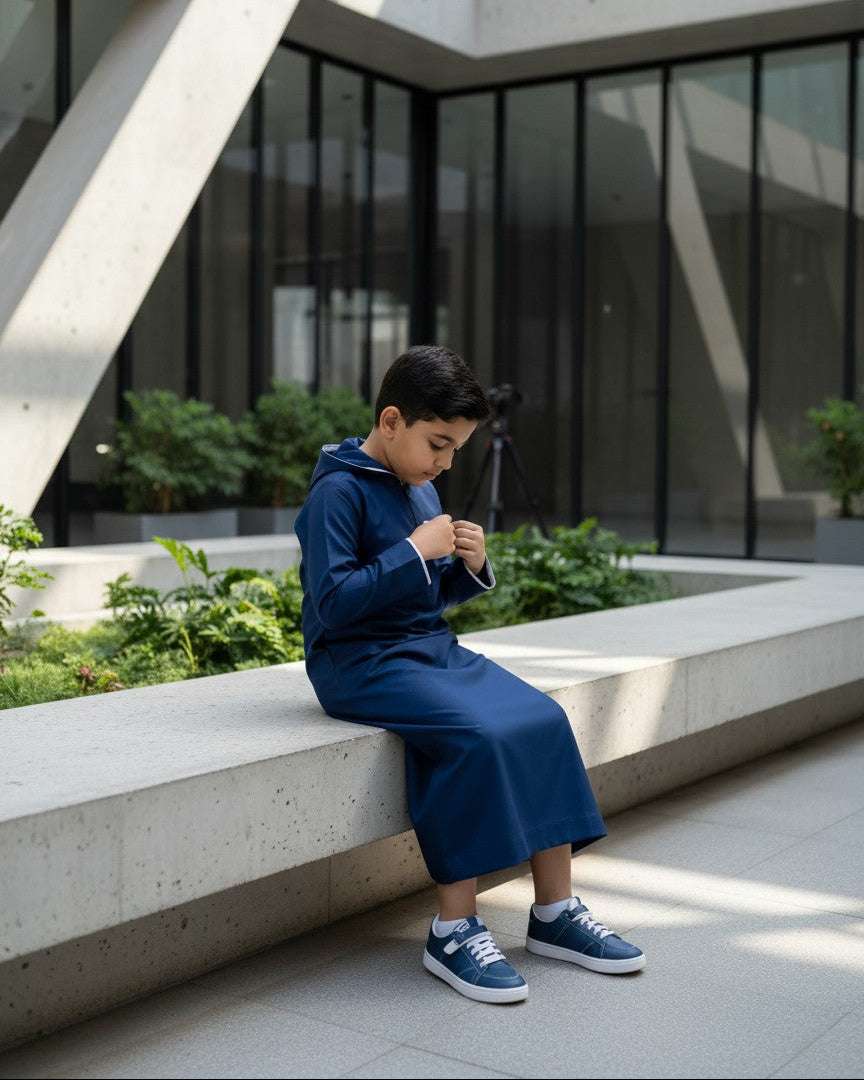 Navy blue hooded thobe with sporty half-zip for boys, worn by a model outdoors
