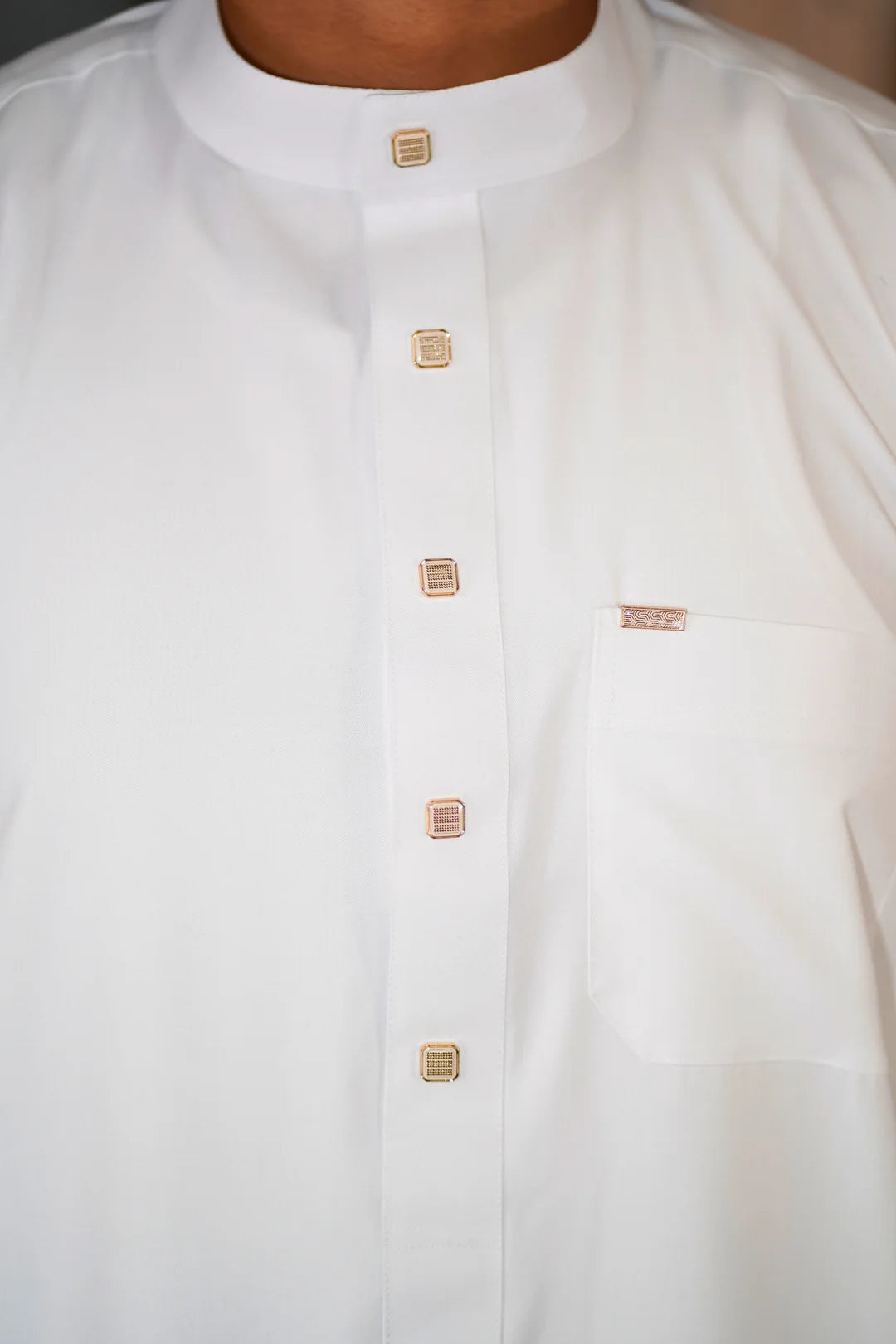 Close up of the elegant light brown buttons on the placket of the men's white jubba