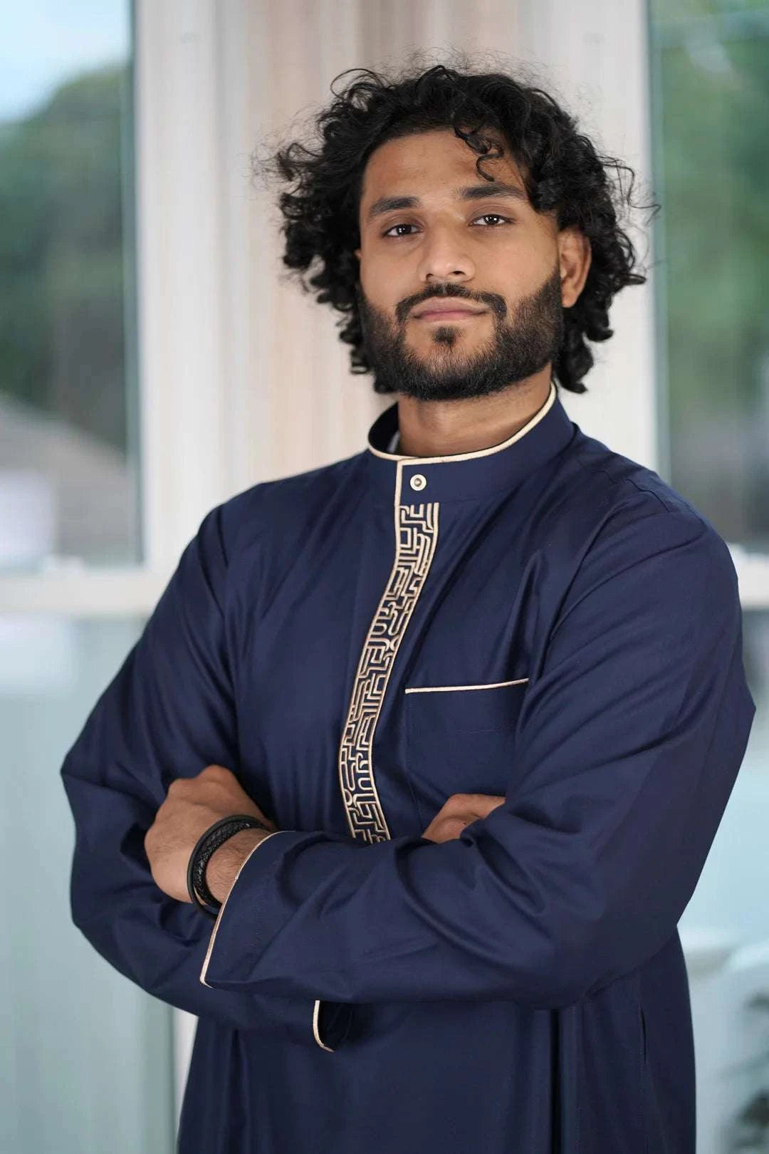Close up of the intricate beige geometric embroidery on the chest and mandarin collar of the navy men's thobe