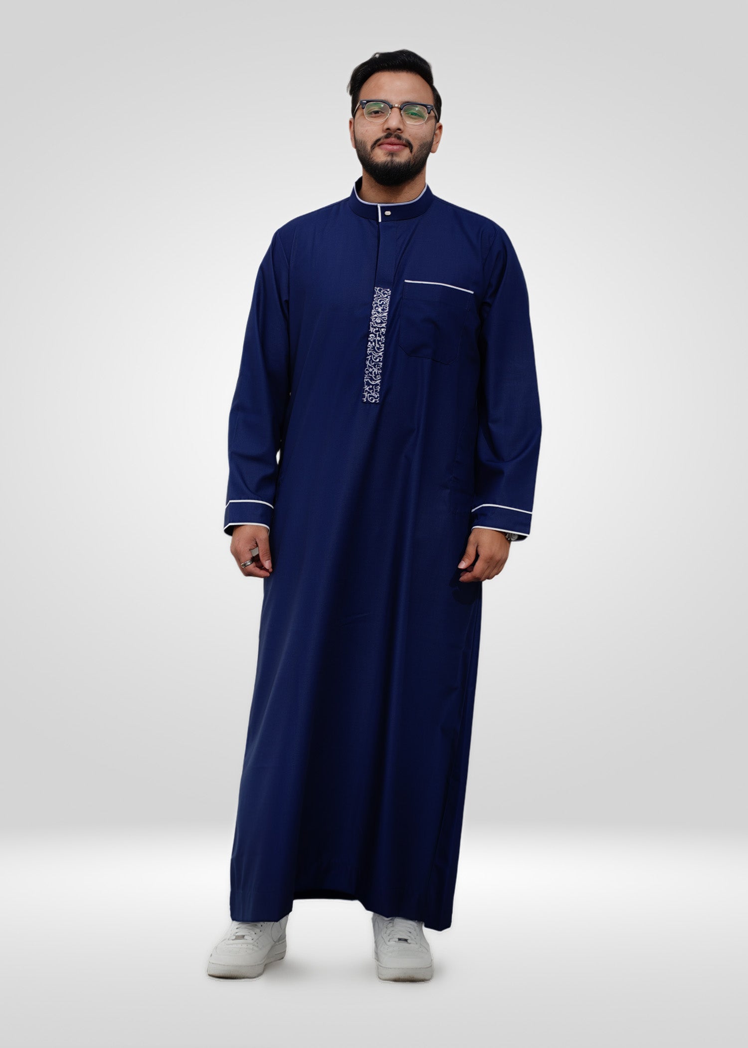 Close up of the intricate white geometric pattern on the chest and collar of the royal blue men's thobe