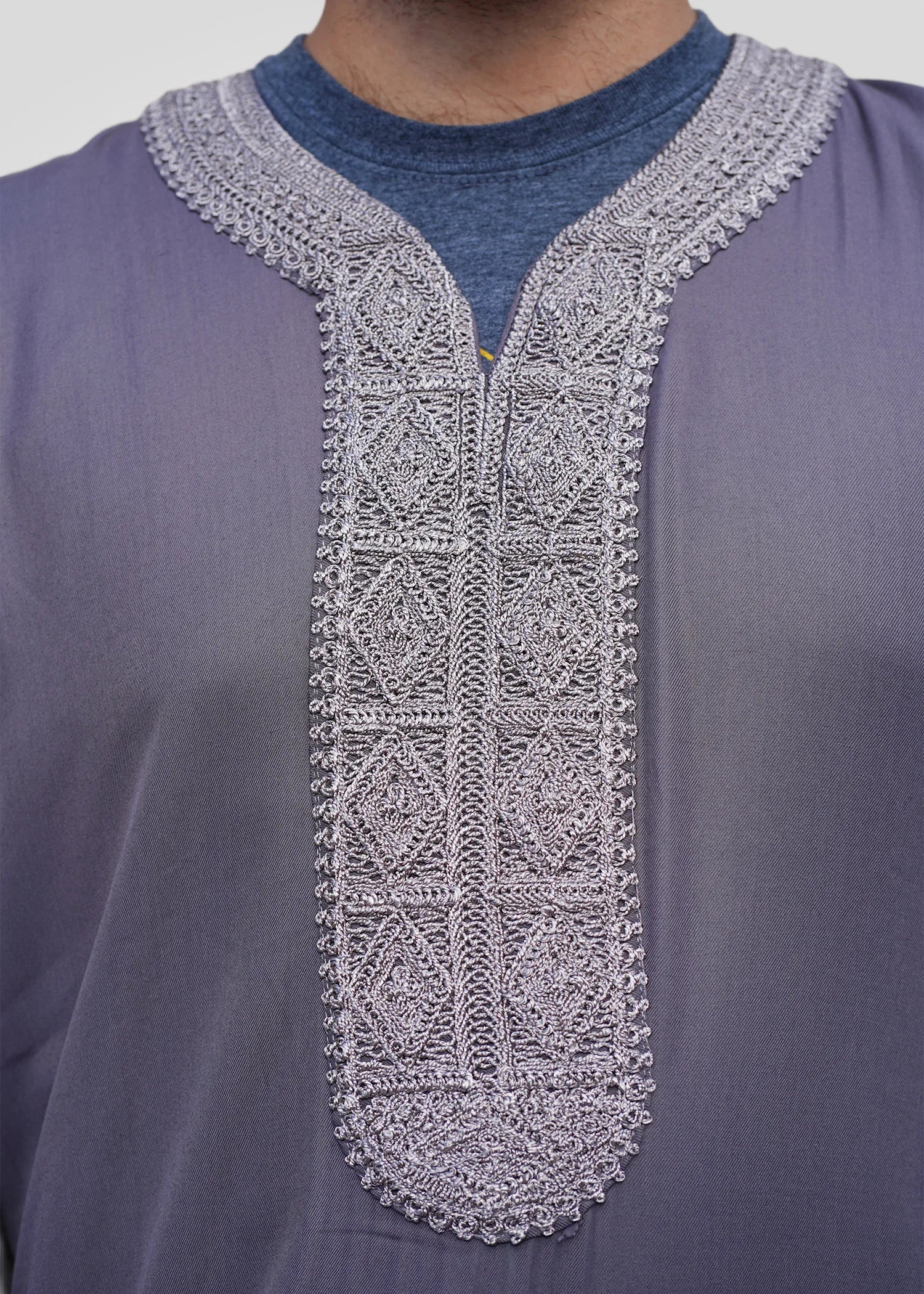 Close up of the intricate silver geometric embroidery on the chest and neckline of the mauve gray men's thobe