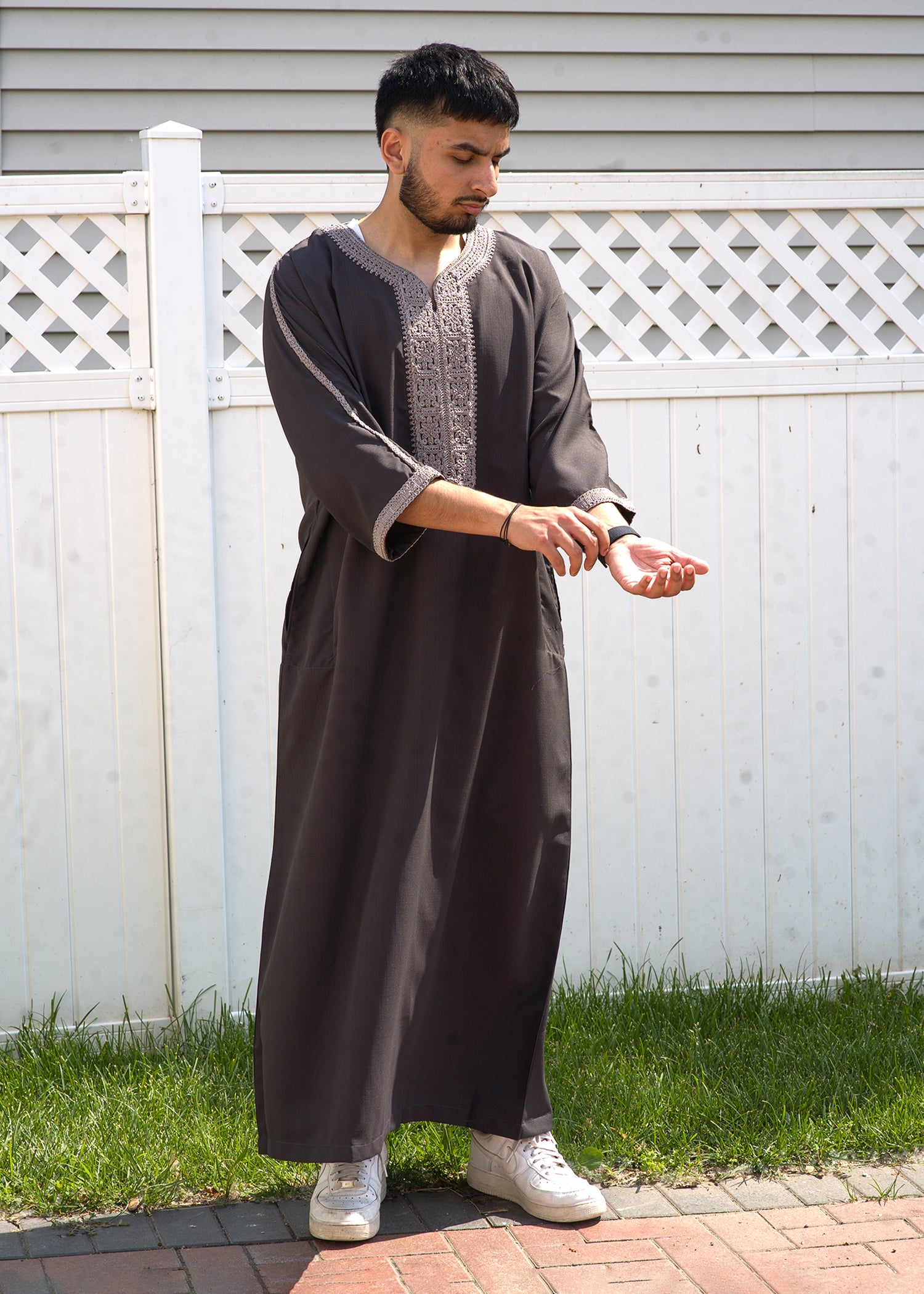 Close up of the intricate silver embroidery on the chest and neckline of the taupe men's thobe