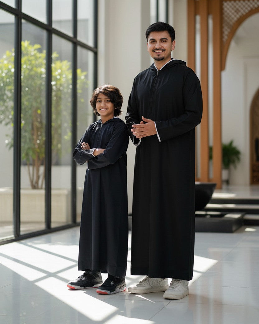 The Topi Wala father and son matching set: black sporty thobes with white piping and hoods.
