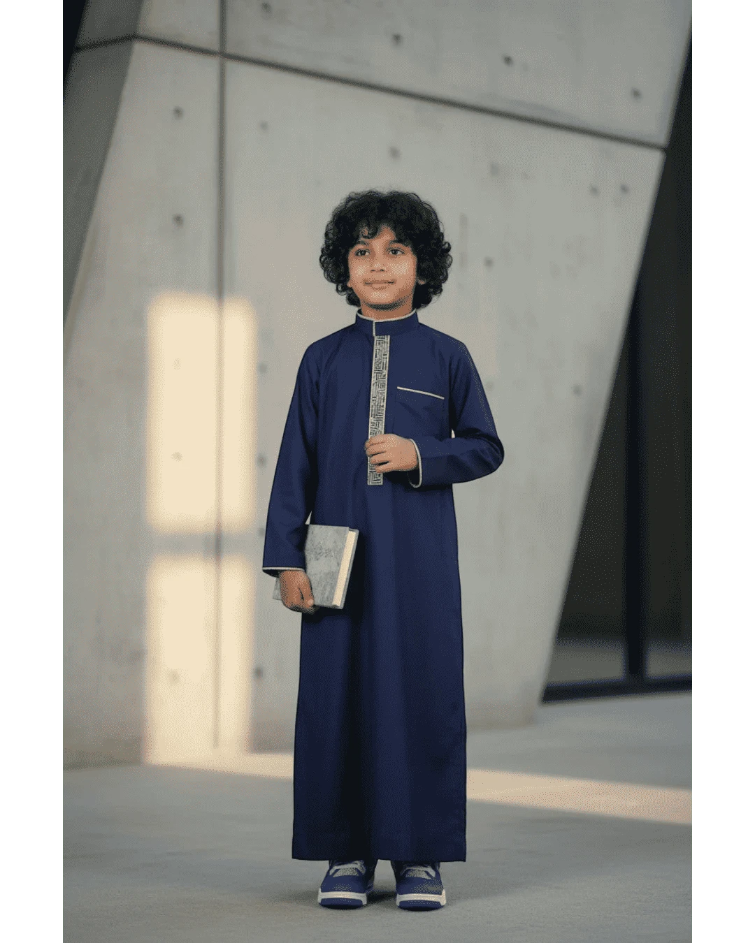 The Topi Wala navy blue boys thobe with beige and gold embroidery on the collar and cuffs.