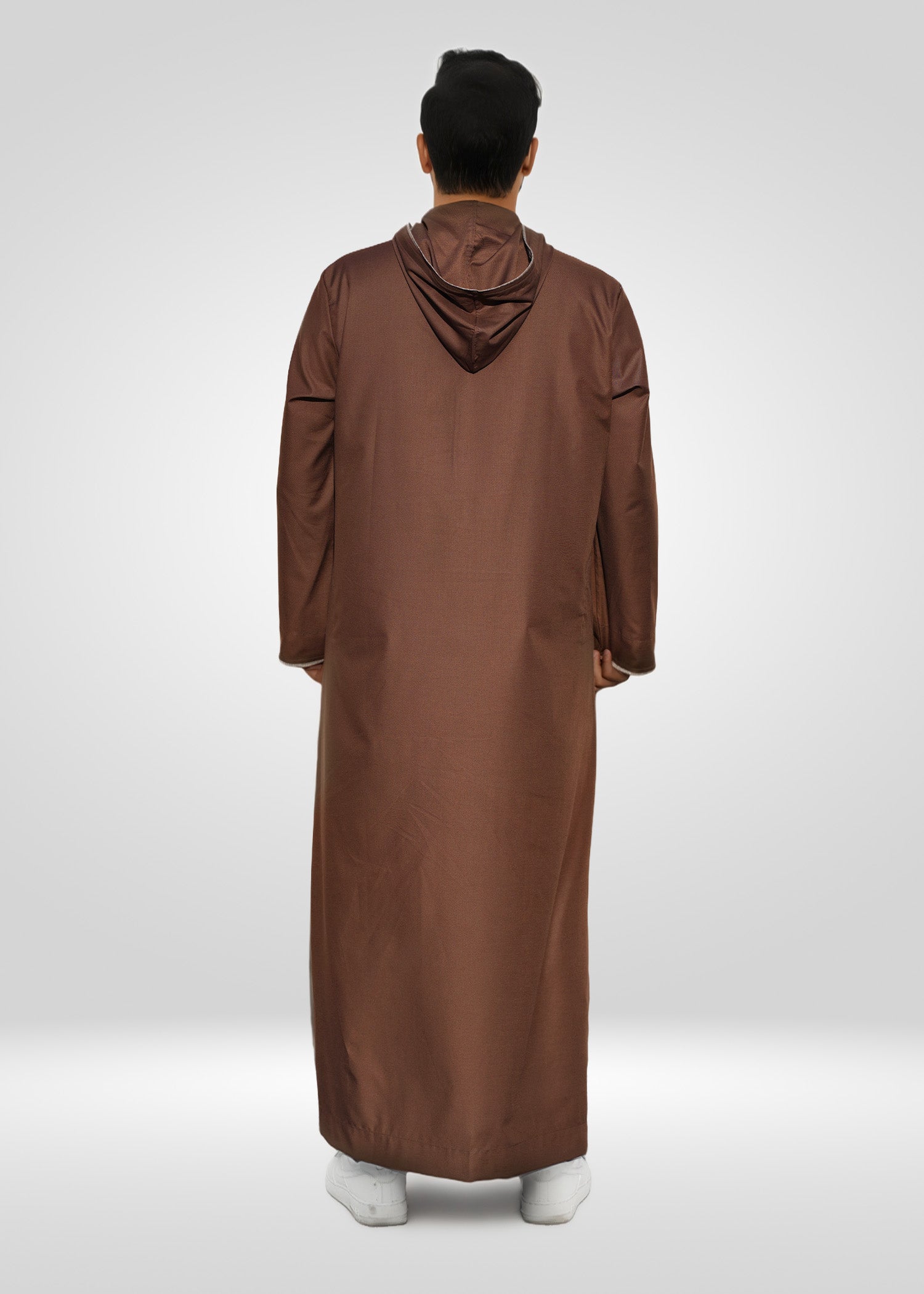 Lifestyle shot of a man wearing the brown hoodie thobe, looking relaxed and stylish