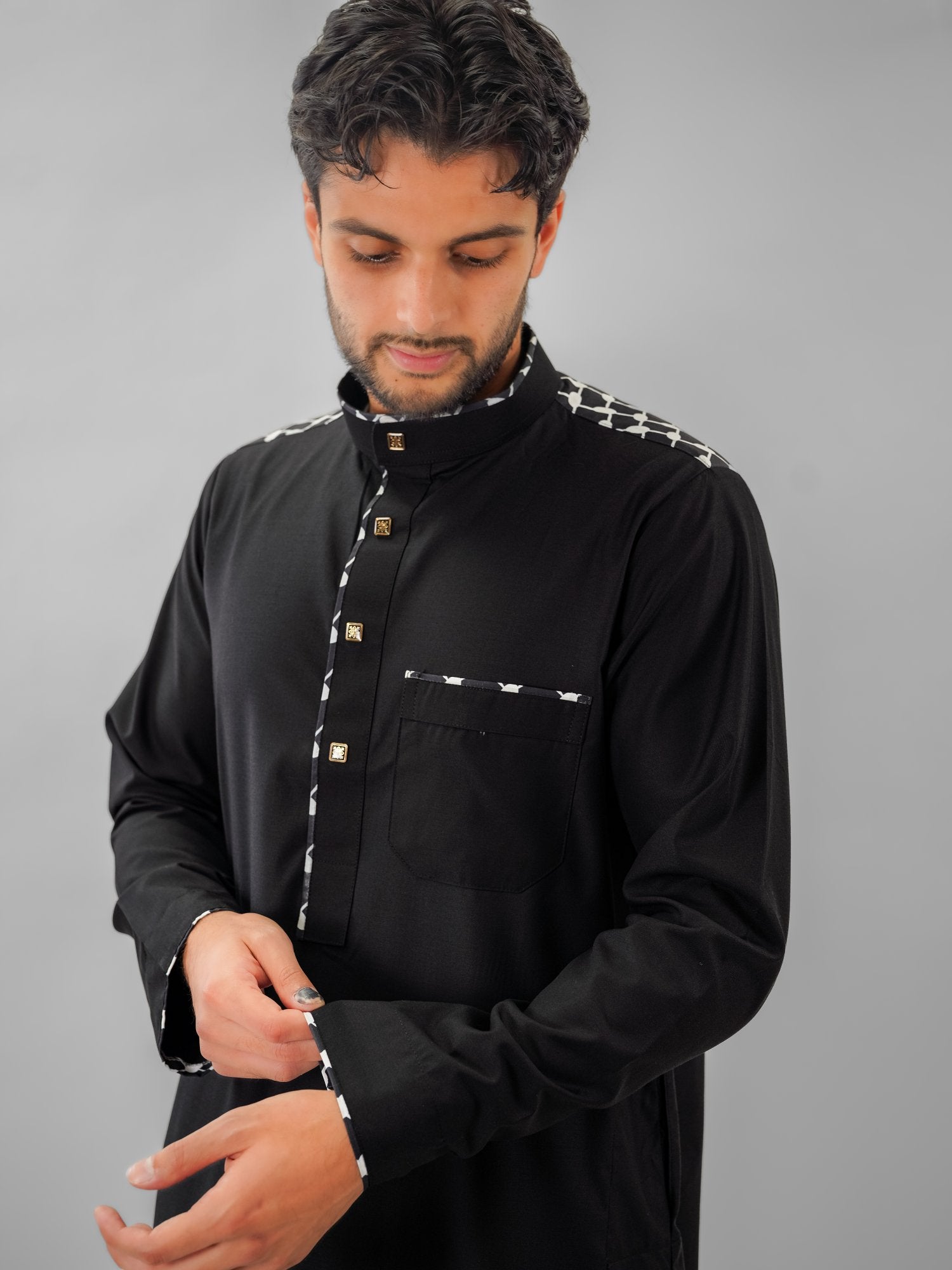 Black embroidered mandarin collar thobe for men, worn by a model outdoors