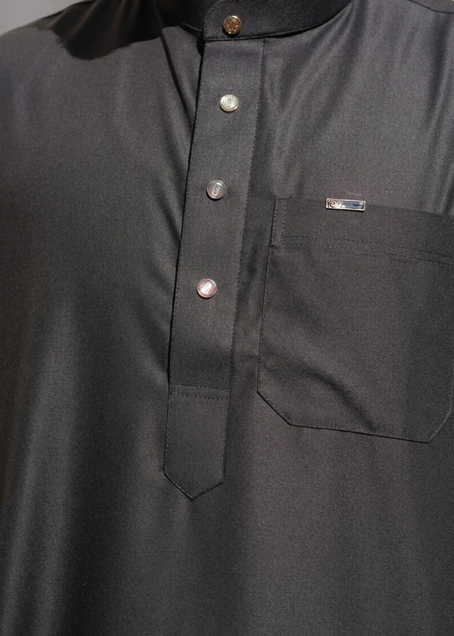 Close up of the buttons and placket on the plain black men's jubba