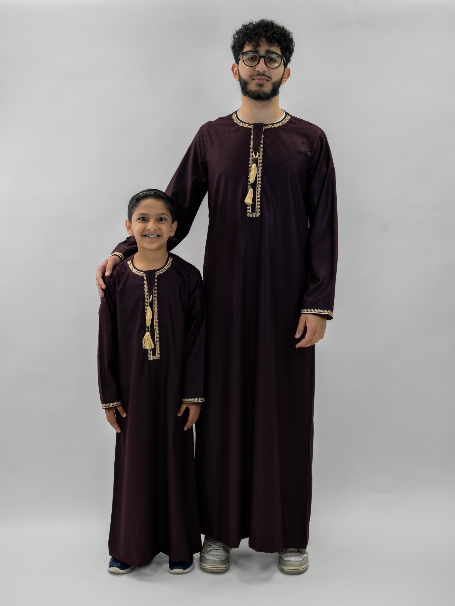 Burgundy emirati v neck with tarboush thobe for men, worn by a model outdoors