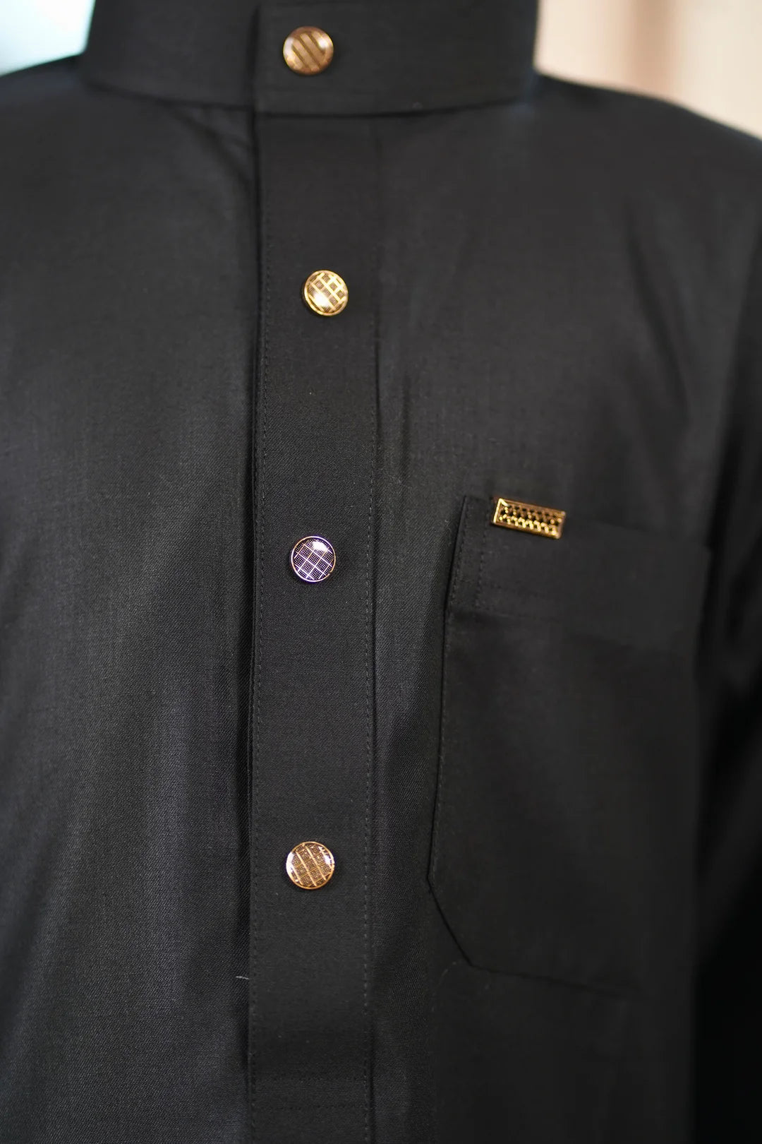 Close up of the mandarin collar and contrasting buttons on the black boys thobe