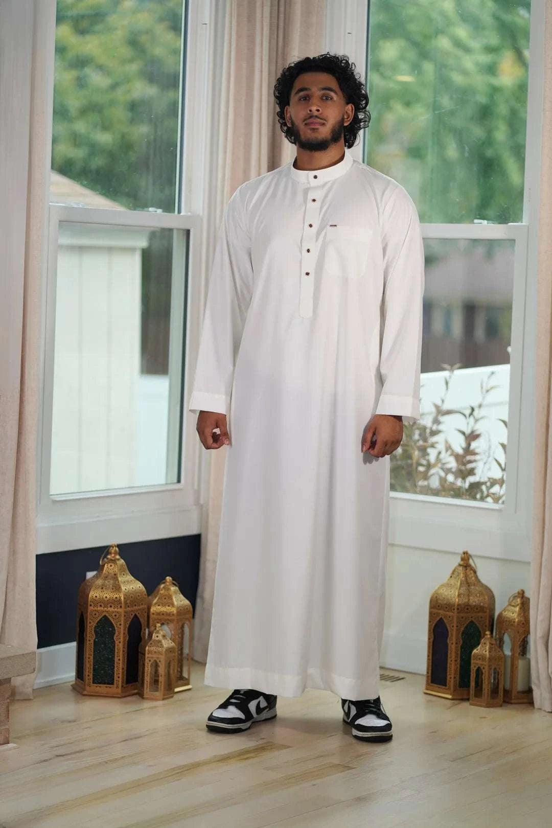 Cream thobe with button placket for men, styled on a model outdoors