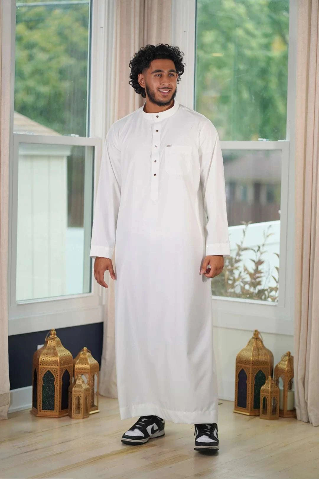 Cream thobe with button placket for men, worn by a model outdoors