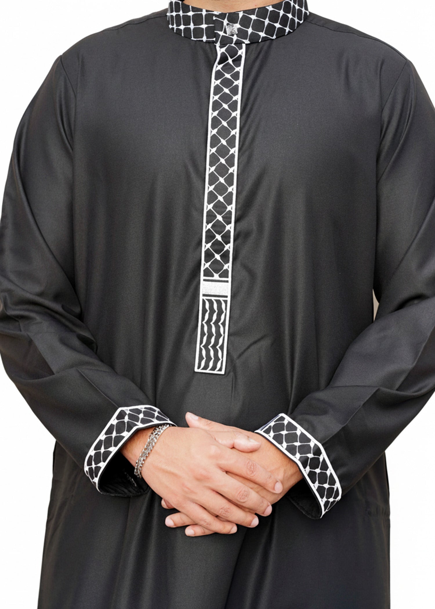 Lifestyle shot of a man wearing the black and white embroidered thobe, looking proud and stylish