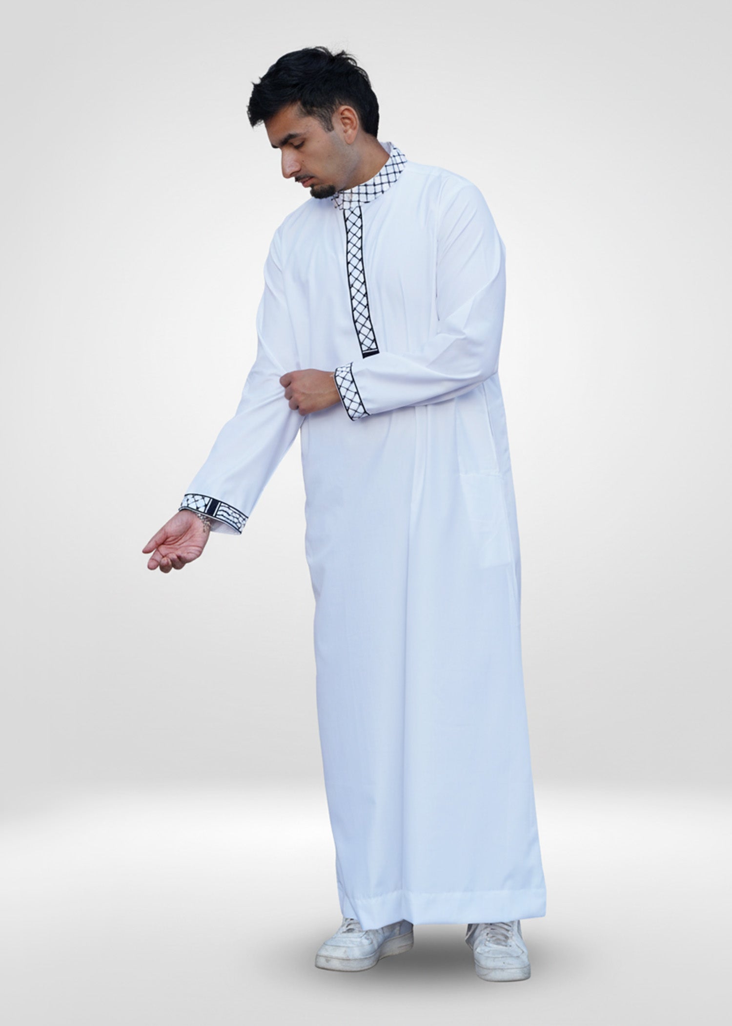 Detail shot of the sleeve cuff featuring matching black checkered embroidery on the white fabric