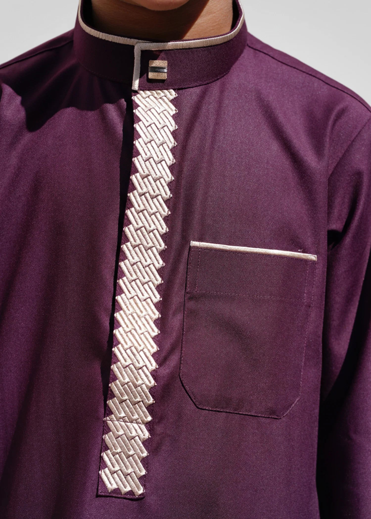 Close up detail of gold tatreez embroidery on the mandarin collar of a boys jubbah
