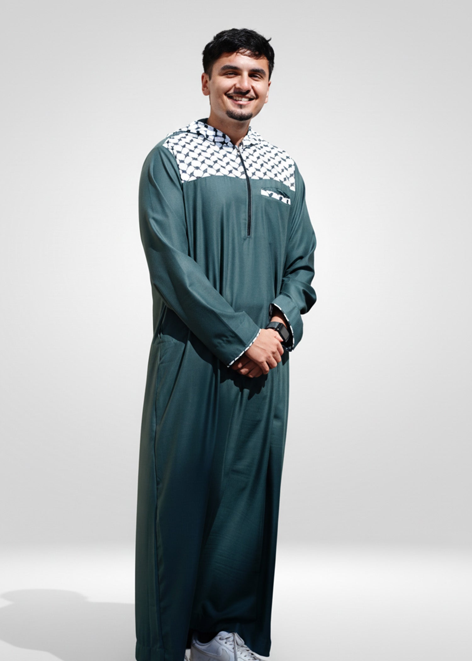 Close up of the bold black and white checkered design on the chest and hood of the green men's jubba