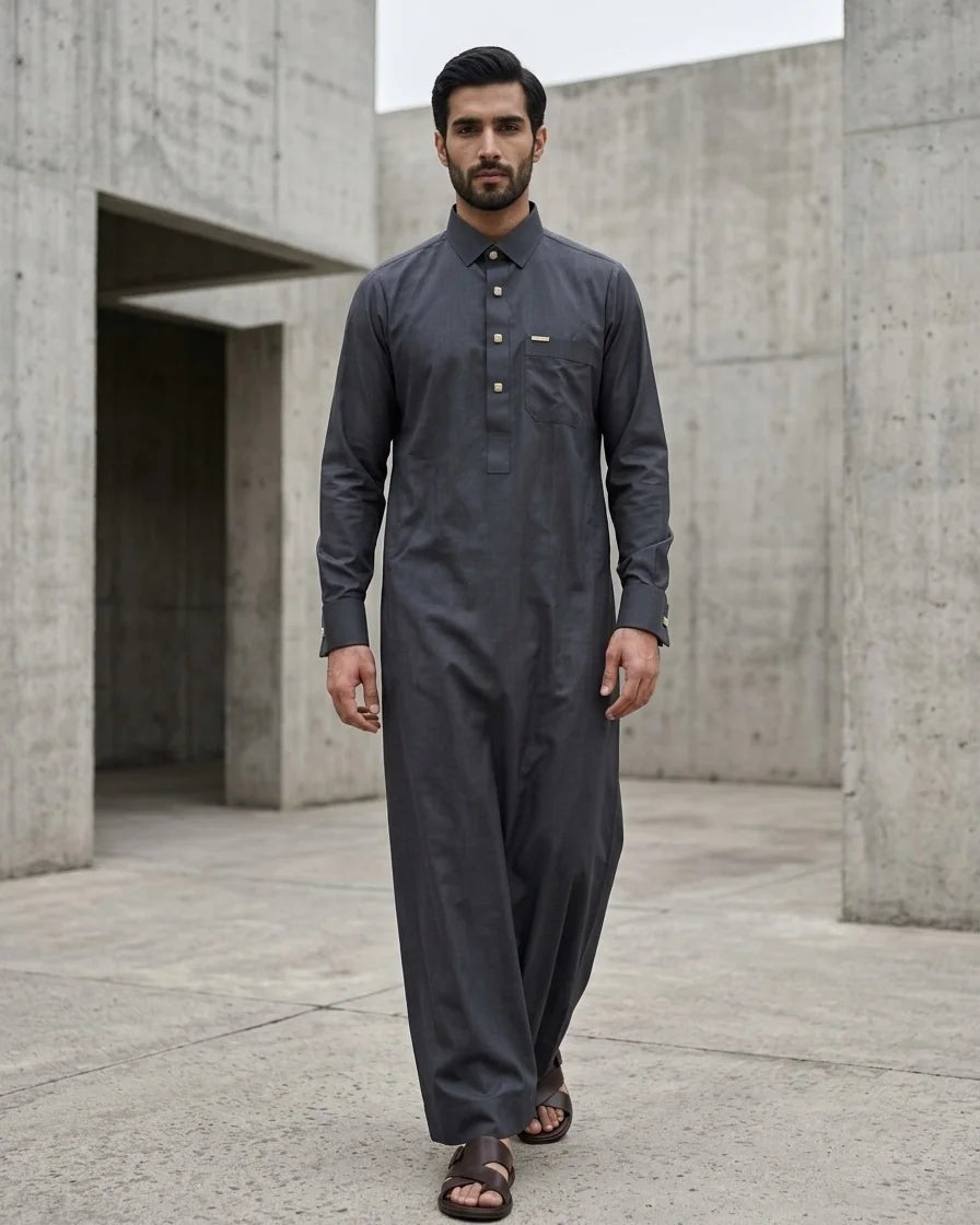 Man walking toward camera in premium graphite grey thobe with shirt collar and square engraved metal buttons, full length — Saudi style men's thobe by The Topiwala
