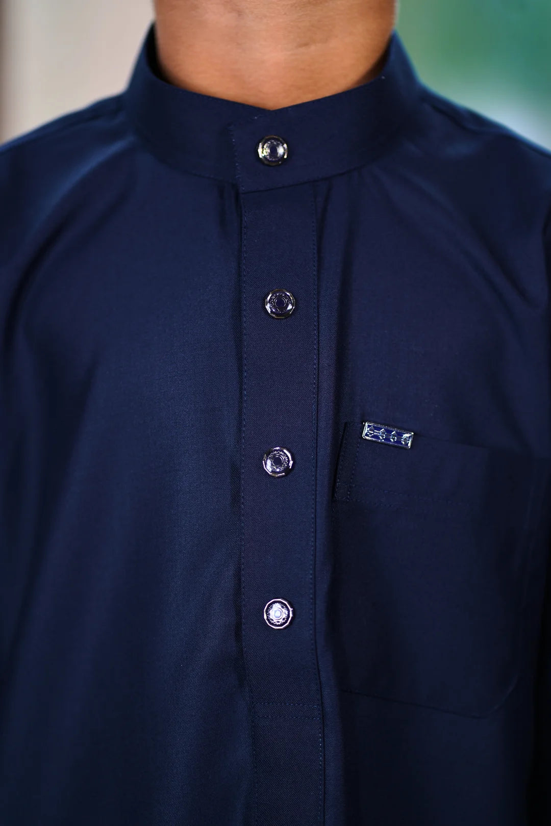 Close up of the mandarin collar and button placket on the navy boys thobe