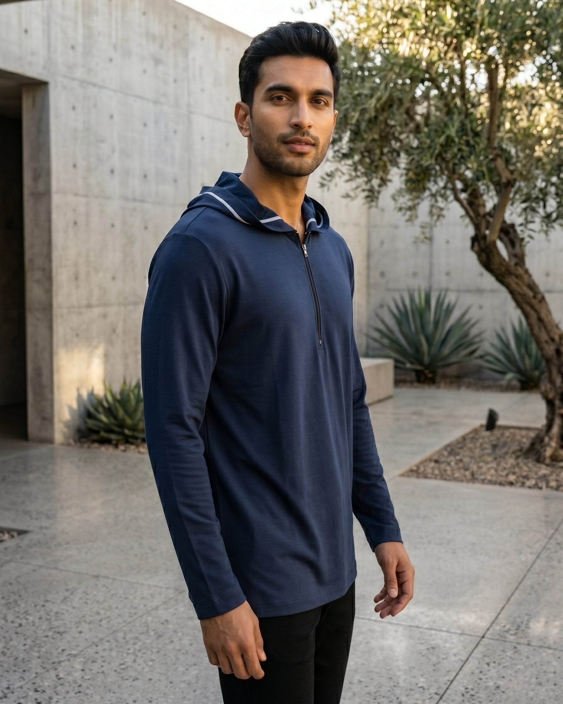 Elegant navy blue men's short kurta leaning against concrete wall, premium modest activewear, comfortable casual Muslim men's apparel, high quality jersey tunic.