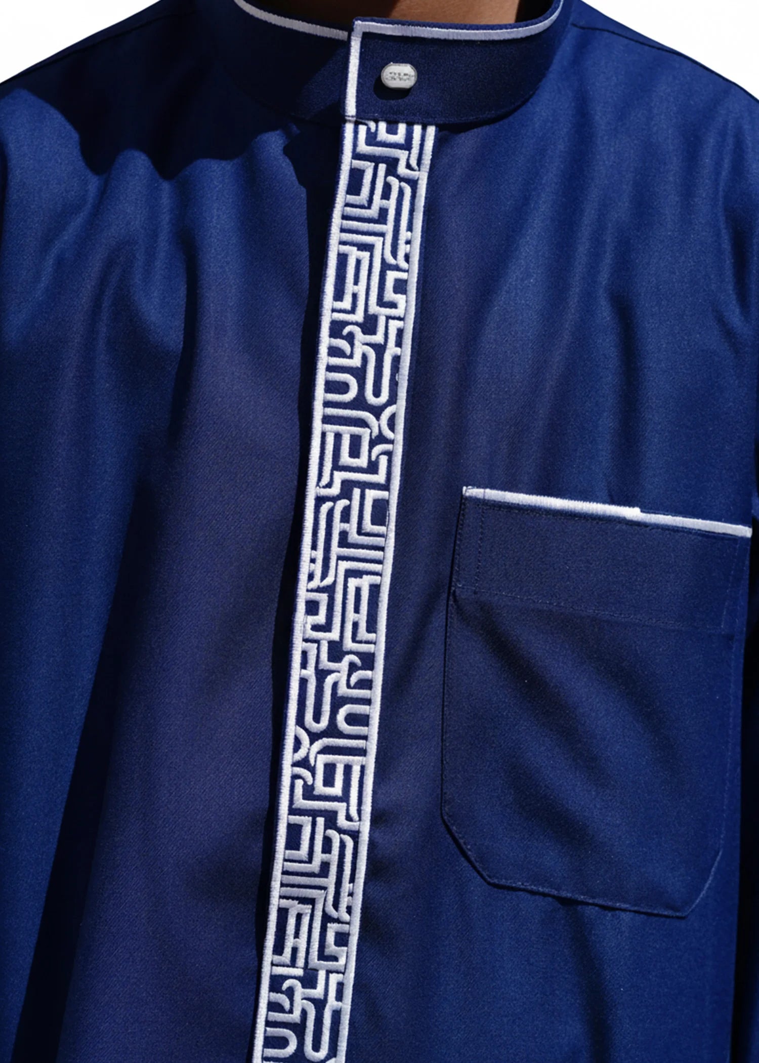Close up of the intricate silver geometric pattern on the chest and collar of the navy boys thobe