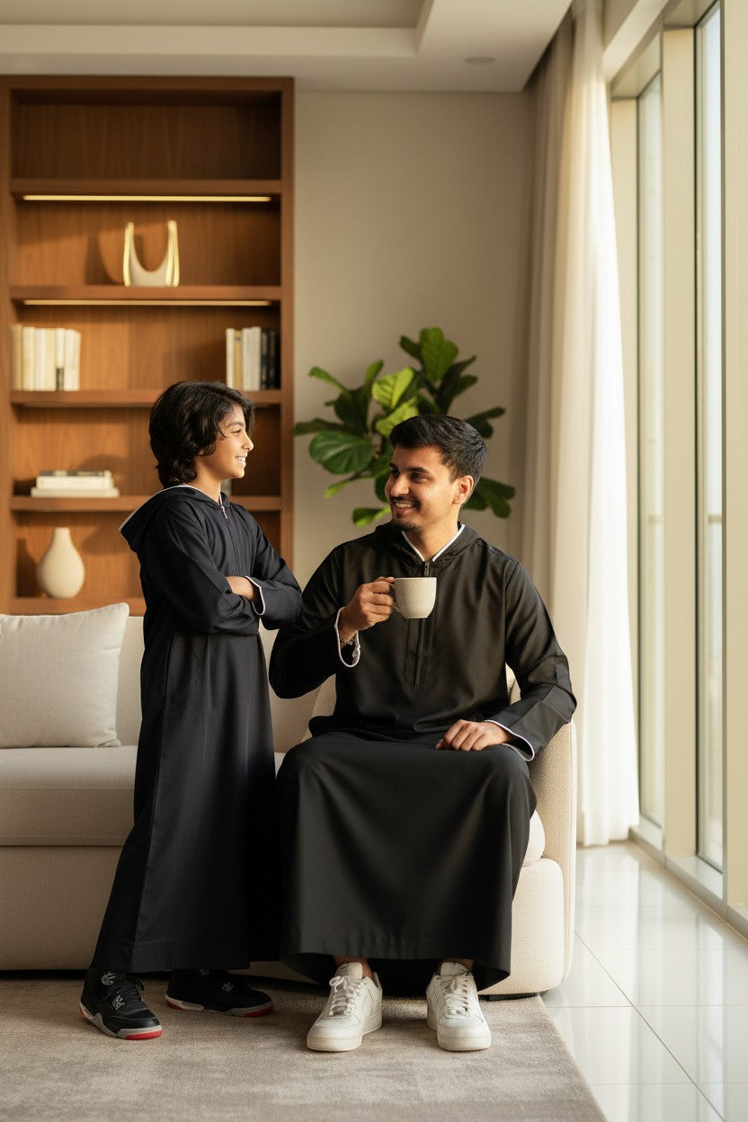 The Topi Wala father and son matching black sporty hoodie thobes with white piping. Casual athleisure wear.