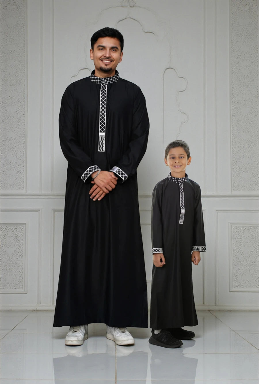 The Topi Wala matching Father and Son set featuring Men's and Kids Black Palestine Embroidered Thobe with white Kufiya pattern details on the mandarin collar and cuffs.