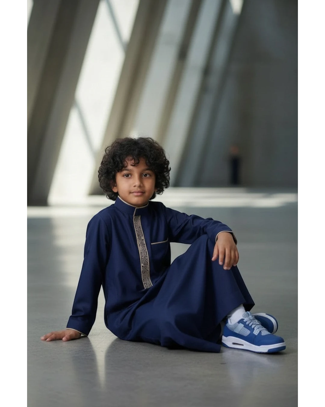 The Topi Wala navy blue boys thobe with beige and gold embroidery on the collar and cuffs. Long sleeves, mandarin collar.