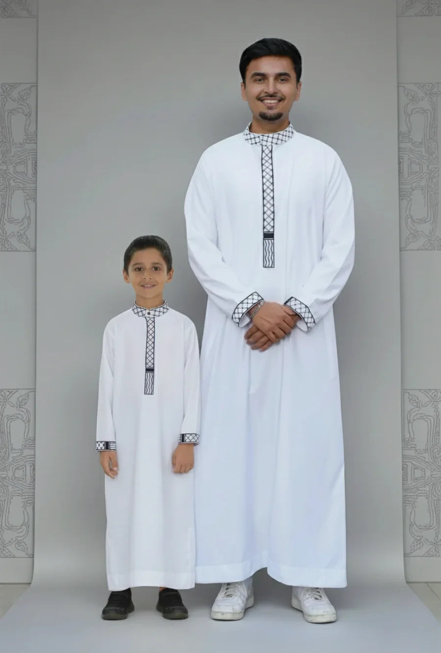 The Topi Wala matching Father and Son set featuring Men's and Kids White Palestine Embroidered Thobe with black Kufiya pattern details on the mandarin collar and cuffs.