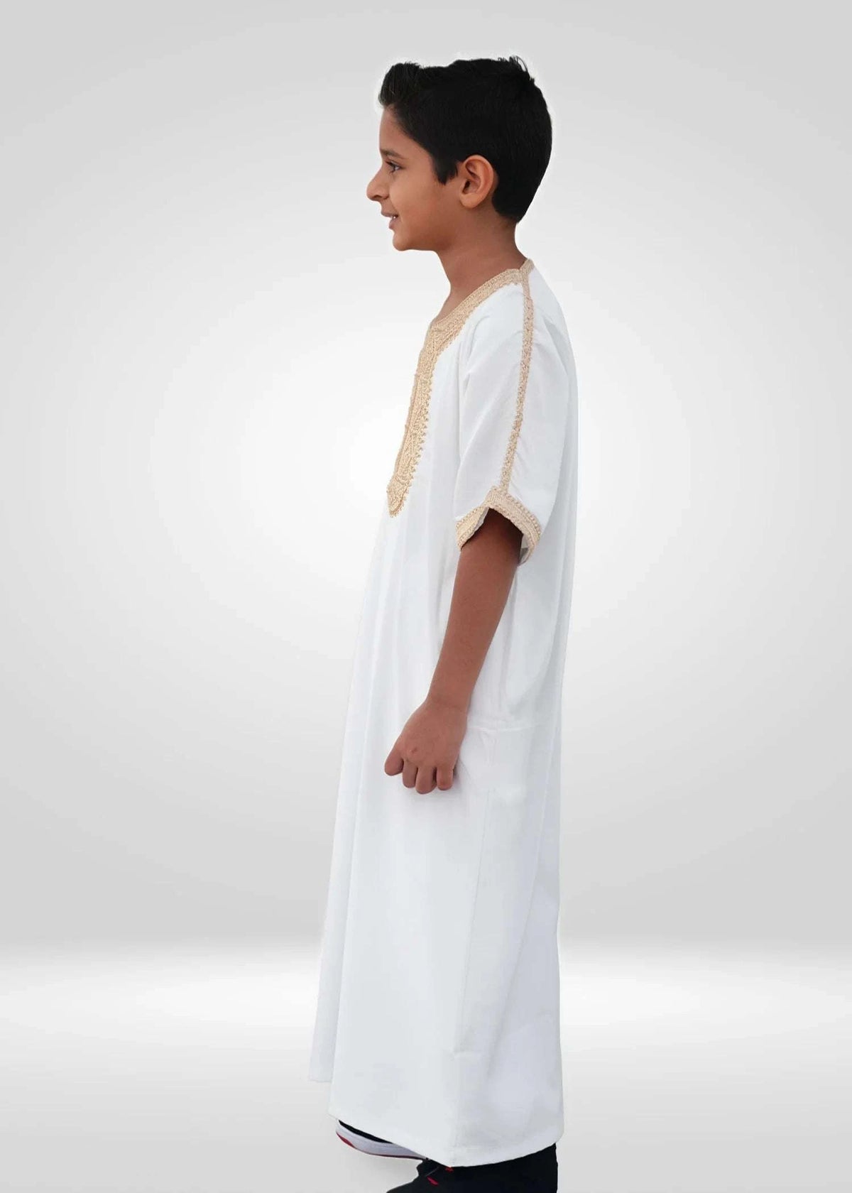 White Moroccan thobe with gold embroidery for boys, worn by a model outdoors